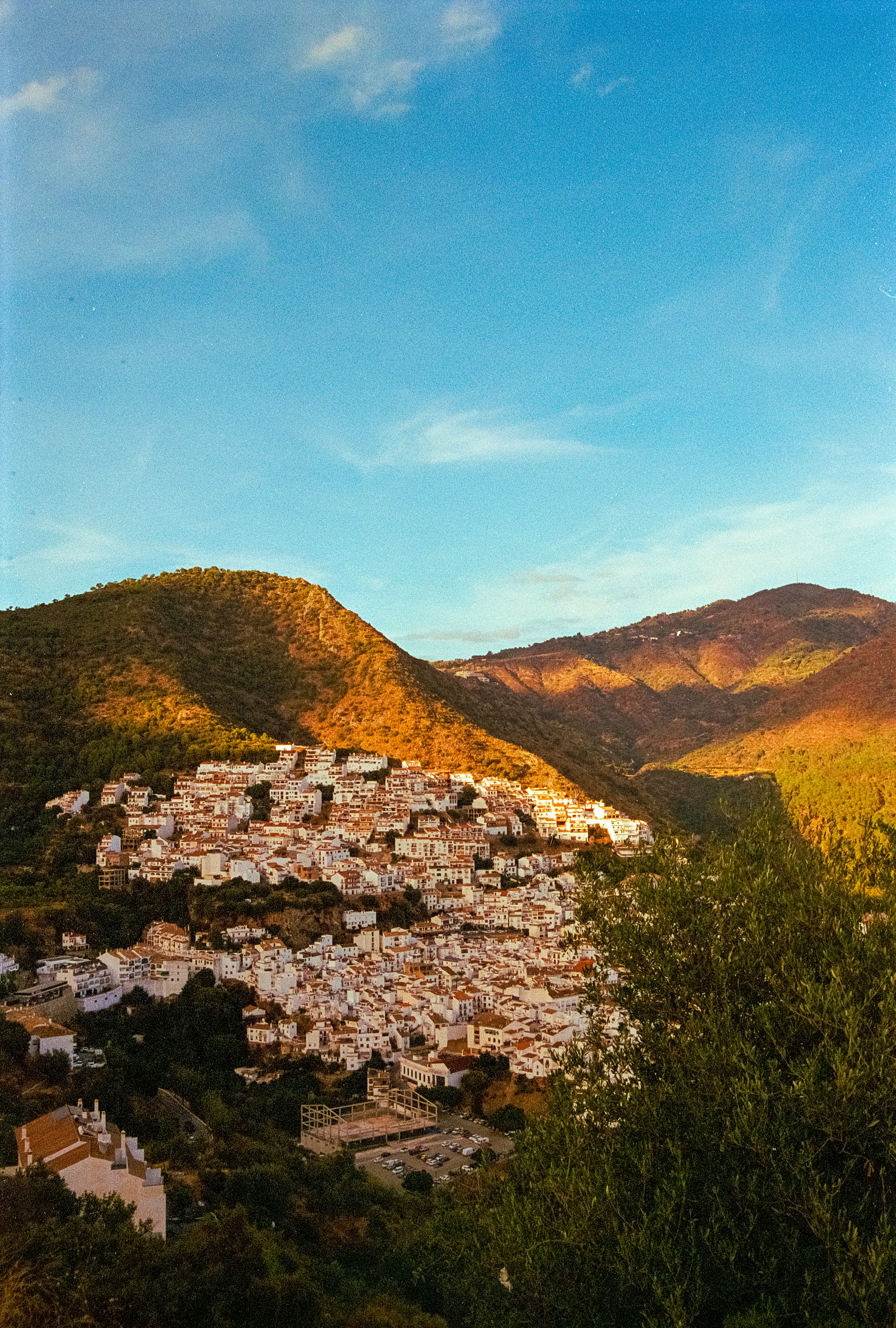 Andalusian white village nestled in sunlit mountains at golden hour.