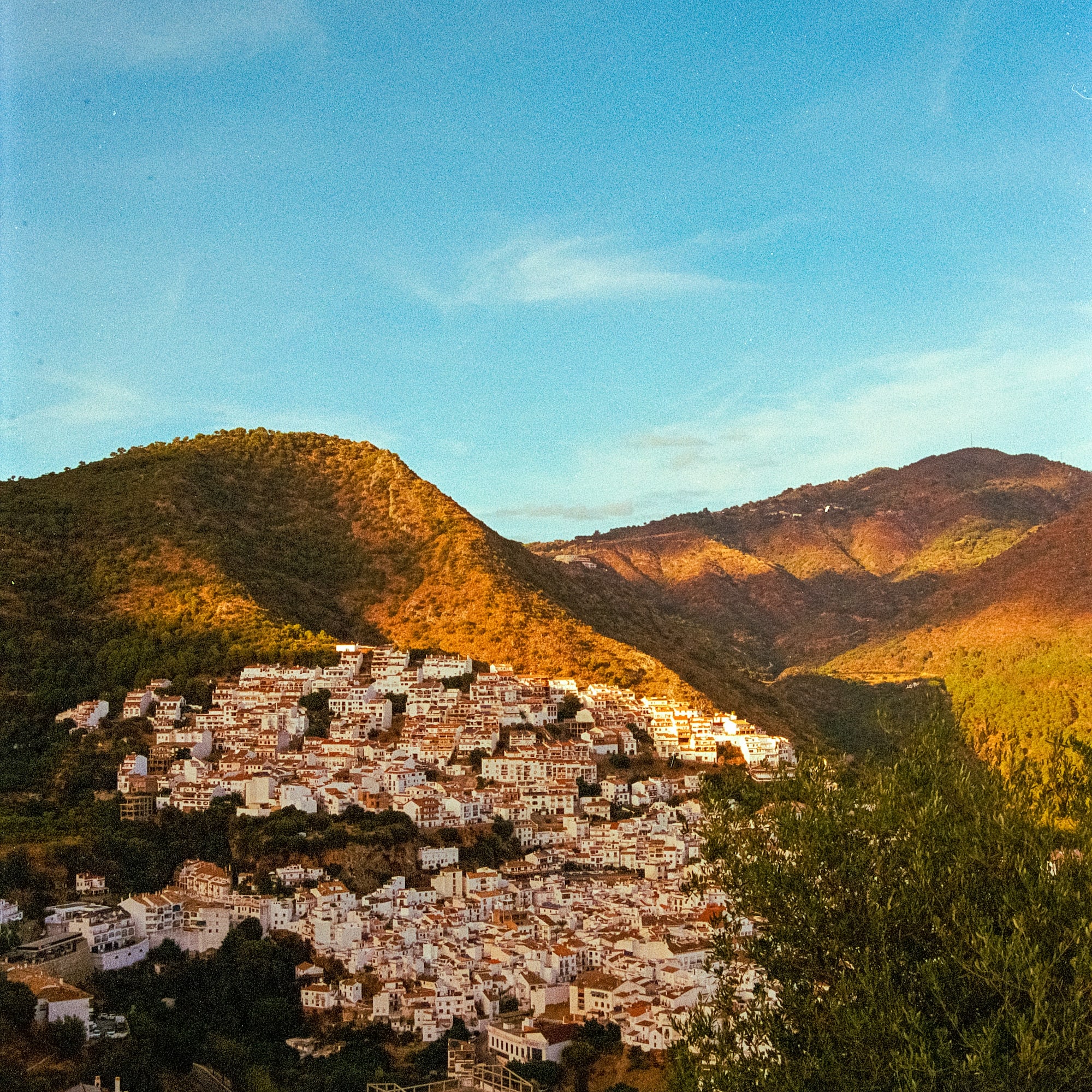 Andalusian white village nestled in sunlit mountains at golden hour.
