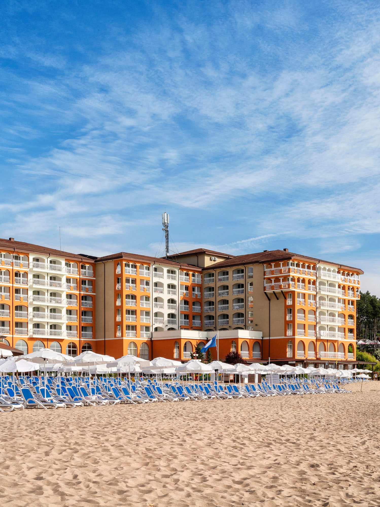 a beach with a large building and chairs