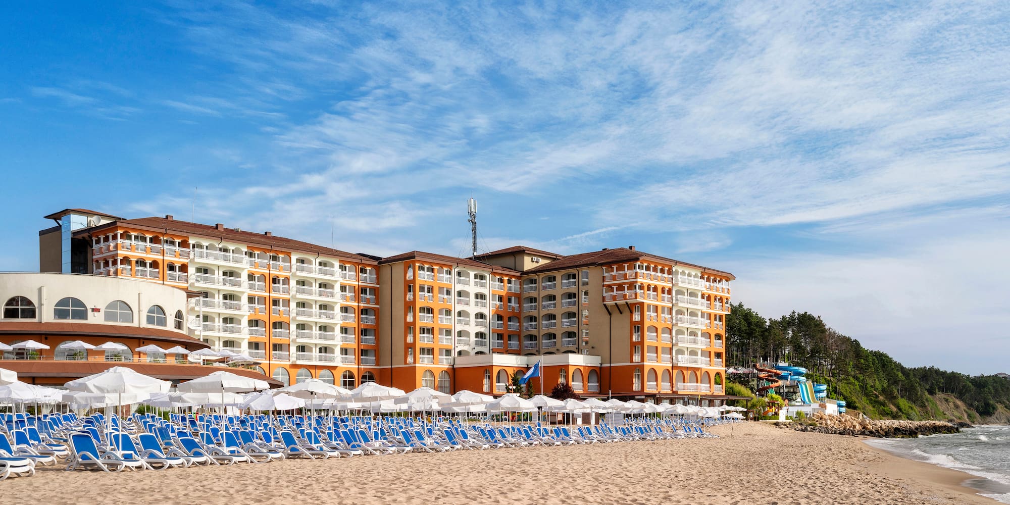 a beach with a large building and chairs