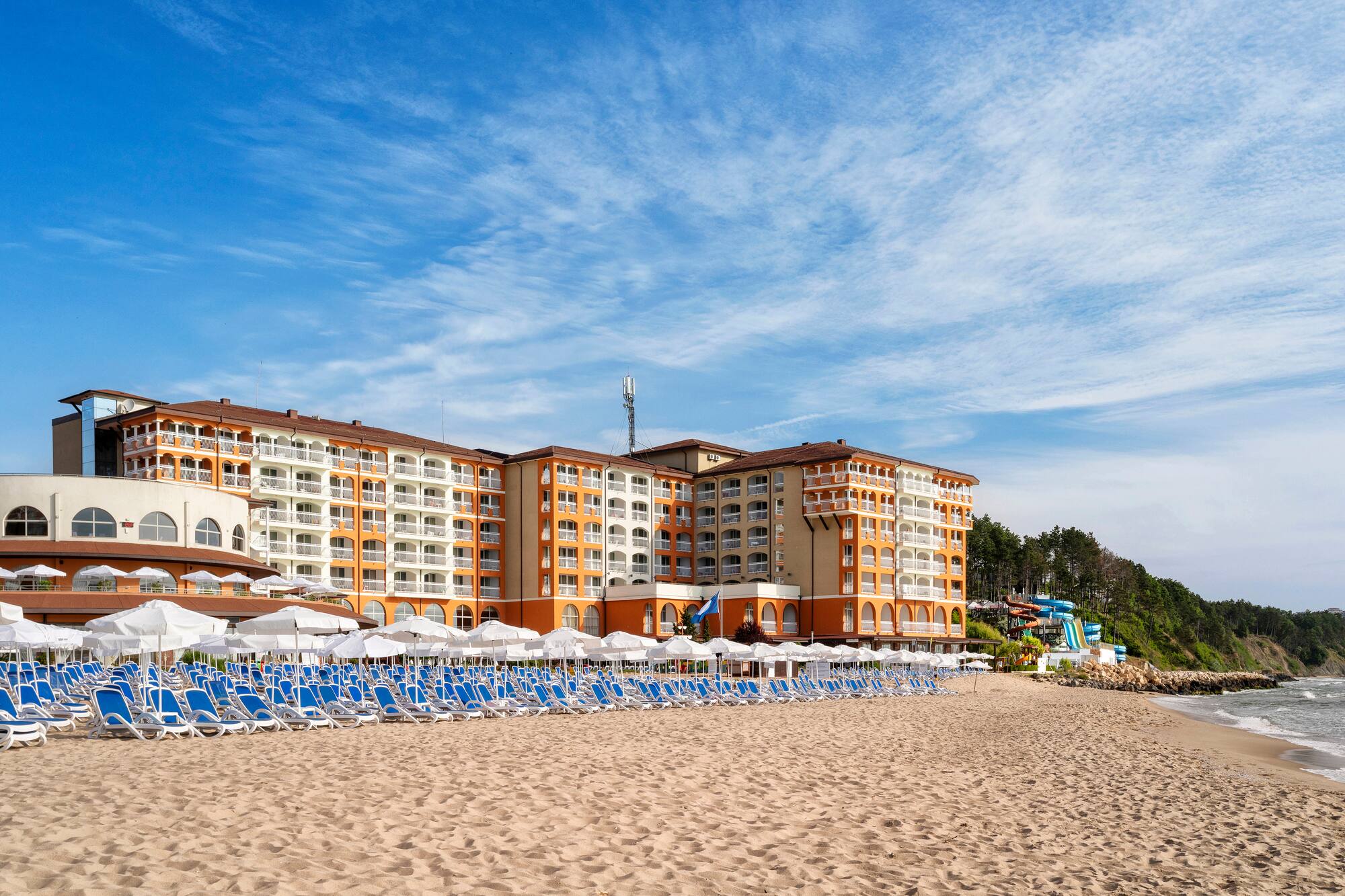 a beach with a large building and chairs