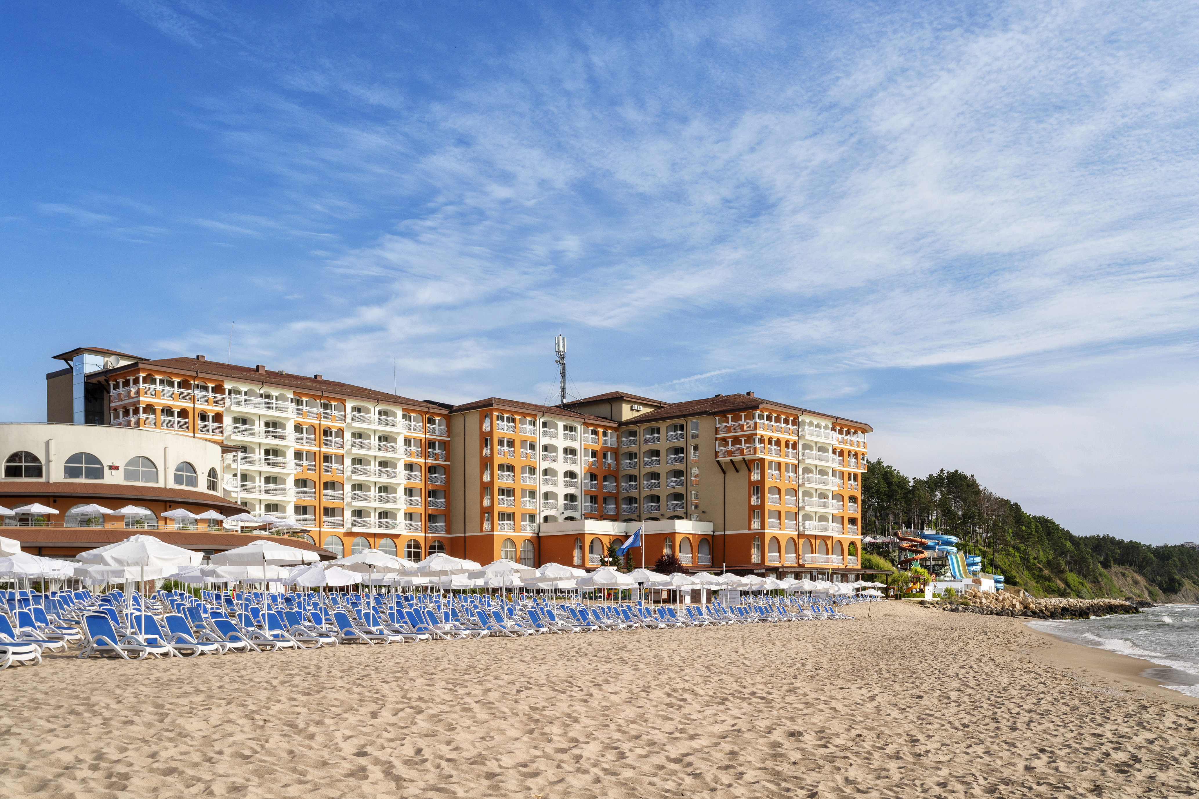 a beach with a large building and chairs