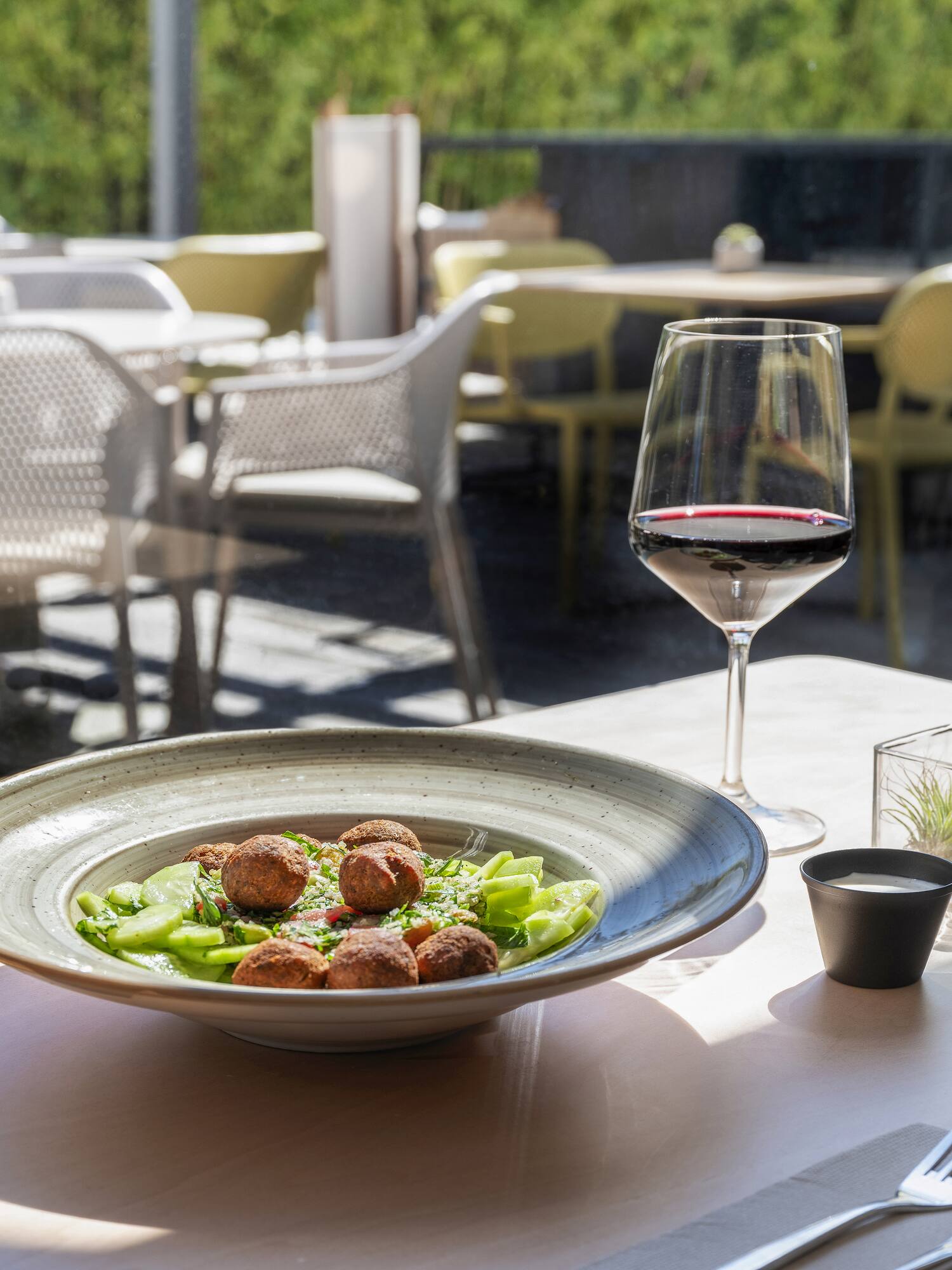 Falafel salad and red wine on a sunny outdoor restaurant patio.