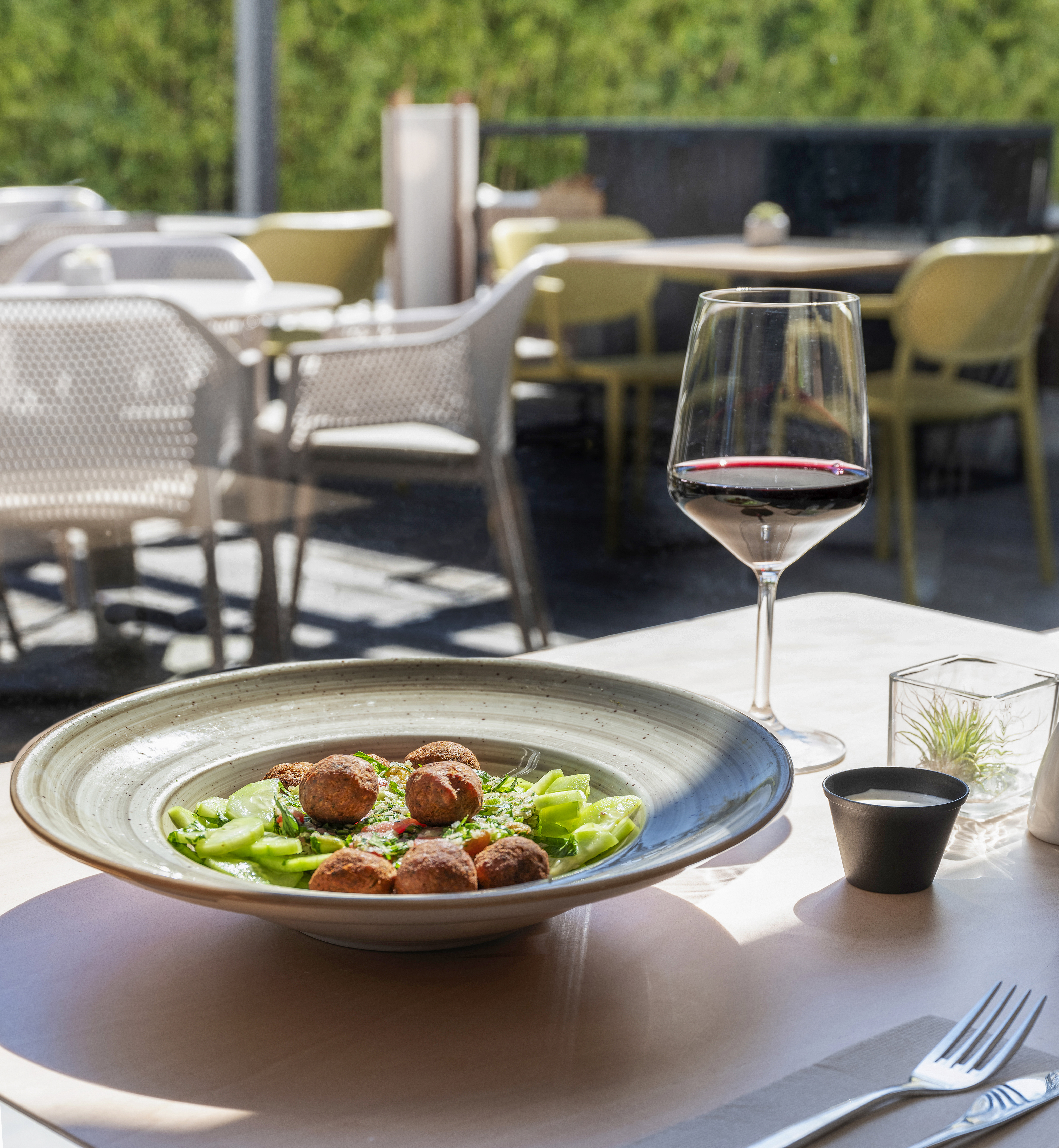 Falafel salad and red wine on a sunny outdoor restaurant patio.