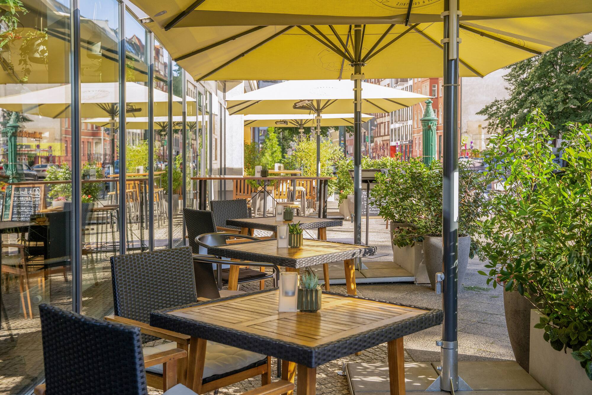 Al fresco dining area with tables, chairs, and yellow umbrellas.
