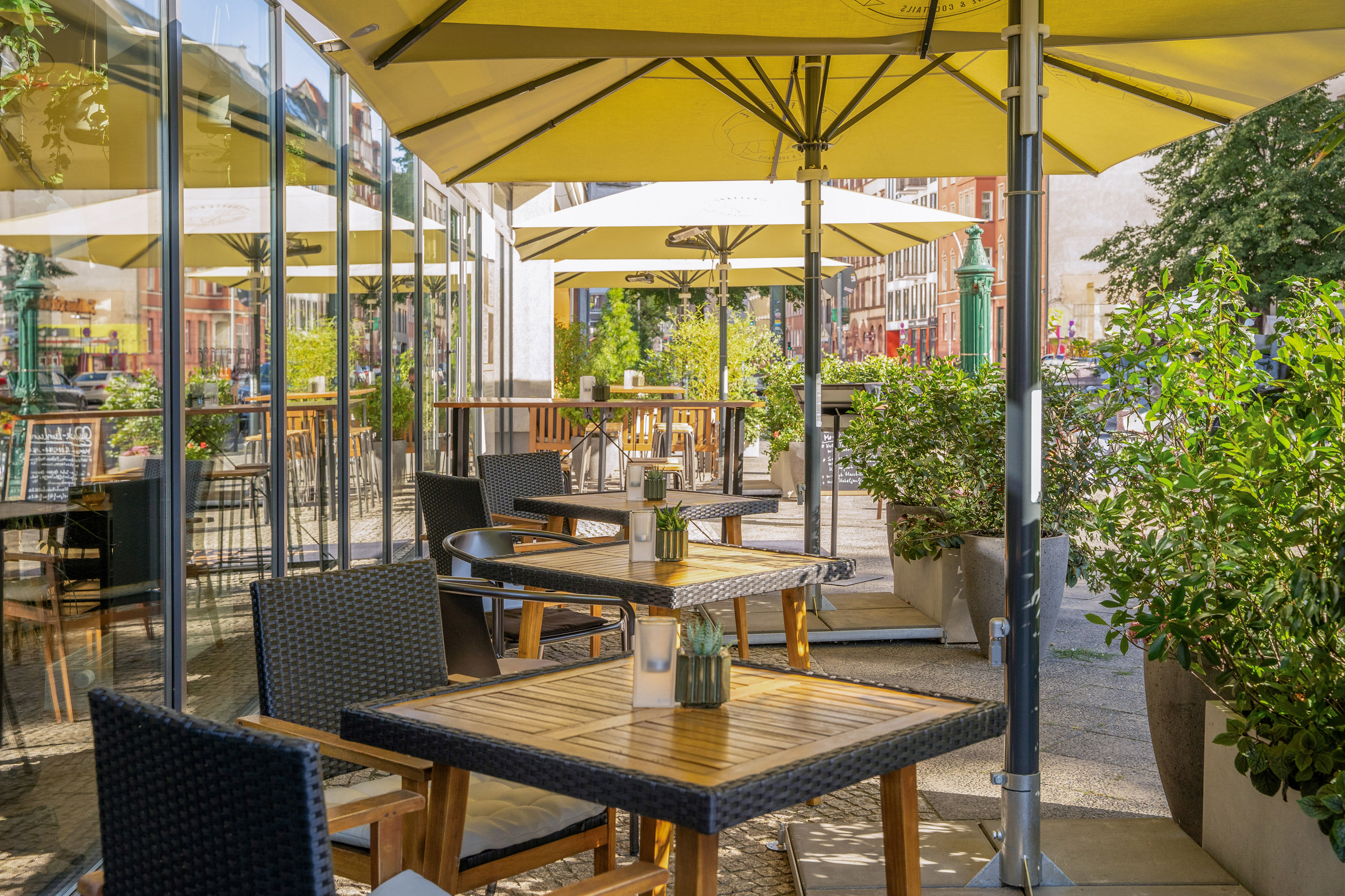 Al fresco dining area with tables, chairs, and yellow umbrellas.