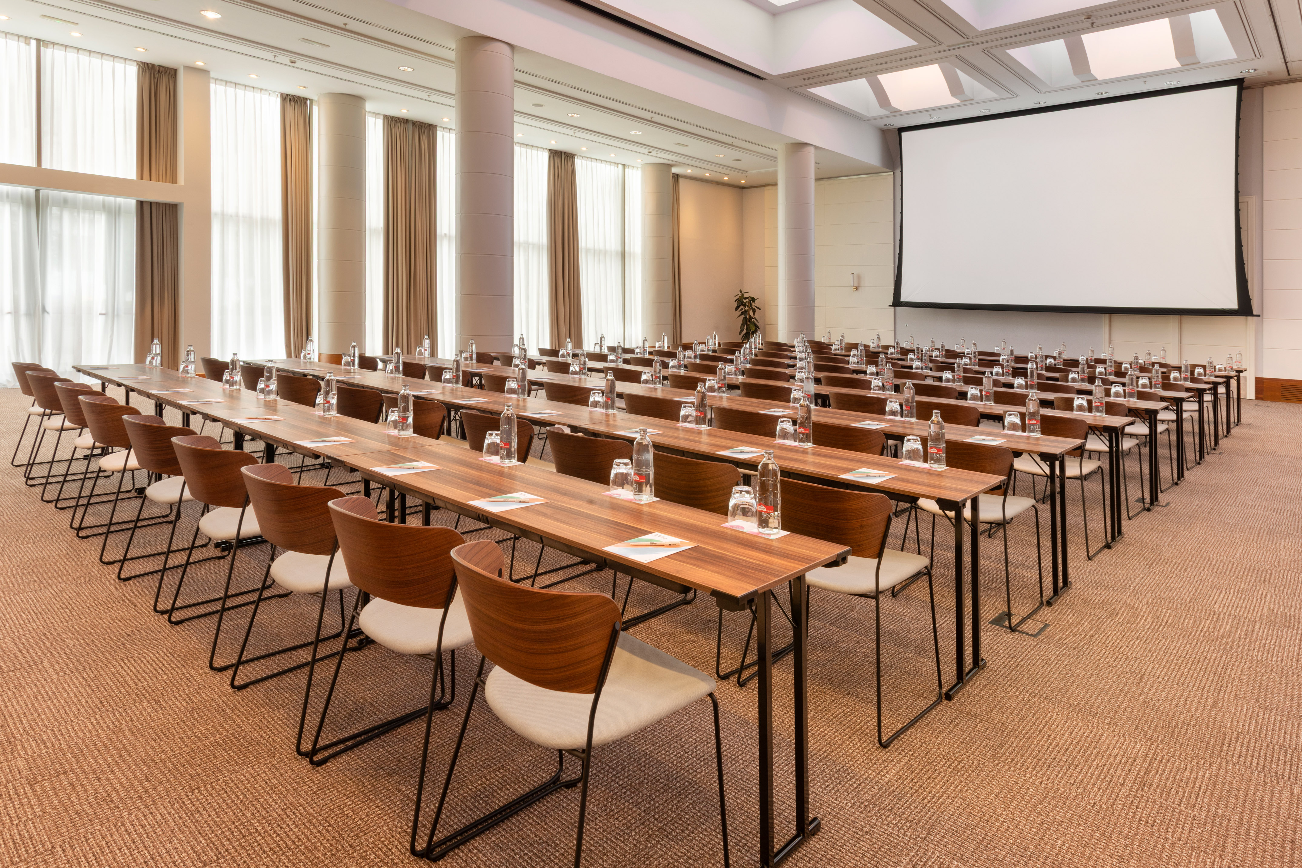 Conference room with tables, chairs, bottled water, and projector screen.
