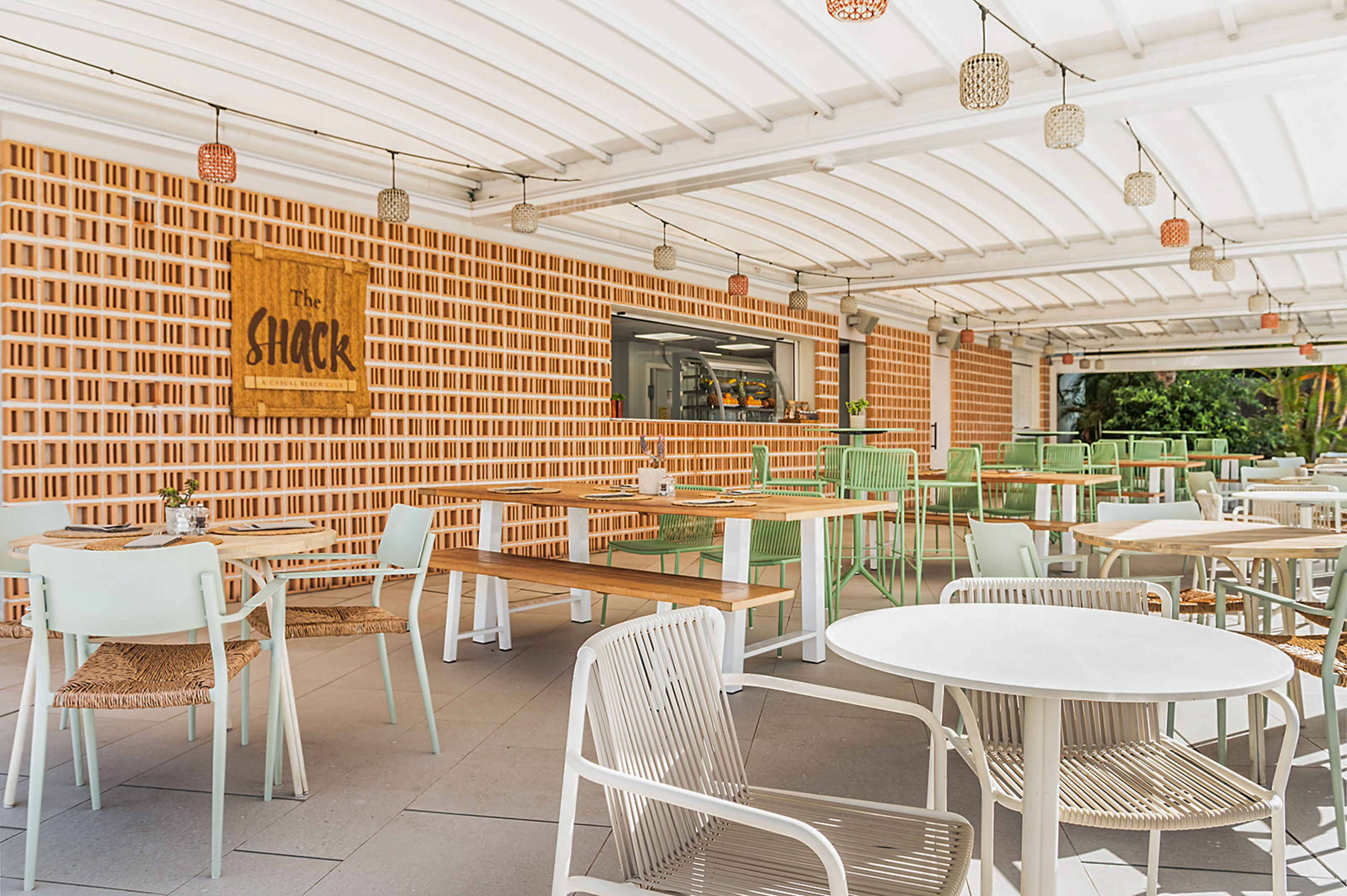 The Shack beach club outdoor patio with brick wall and green chairs.