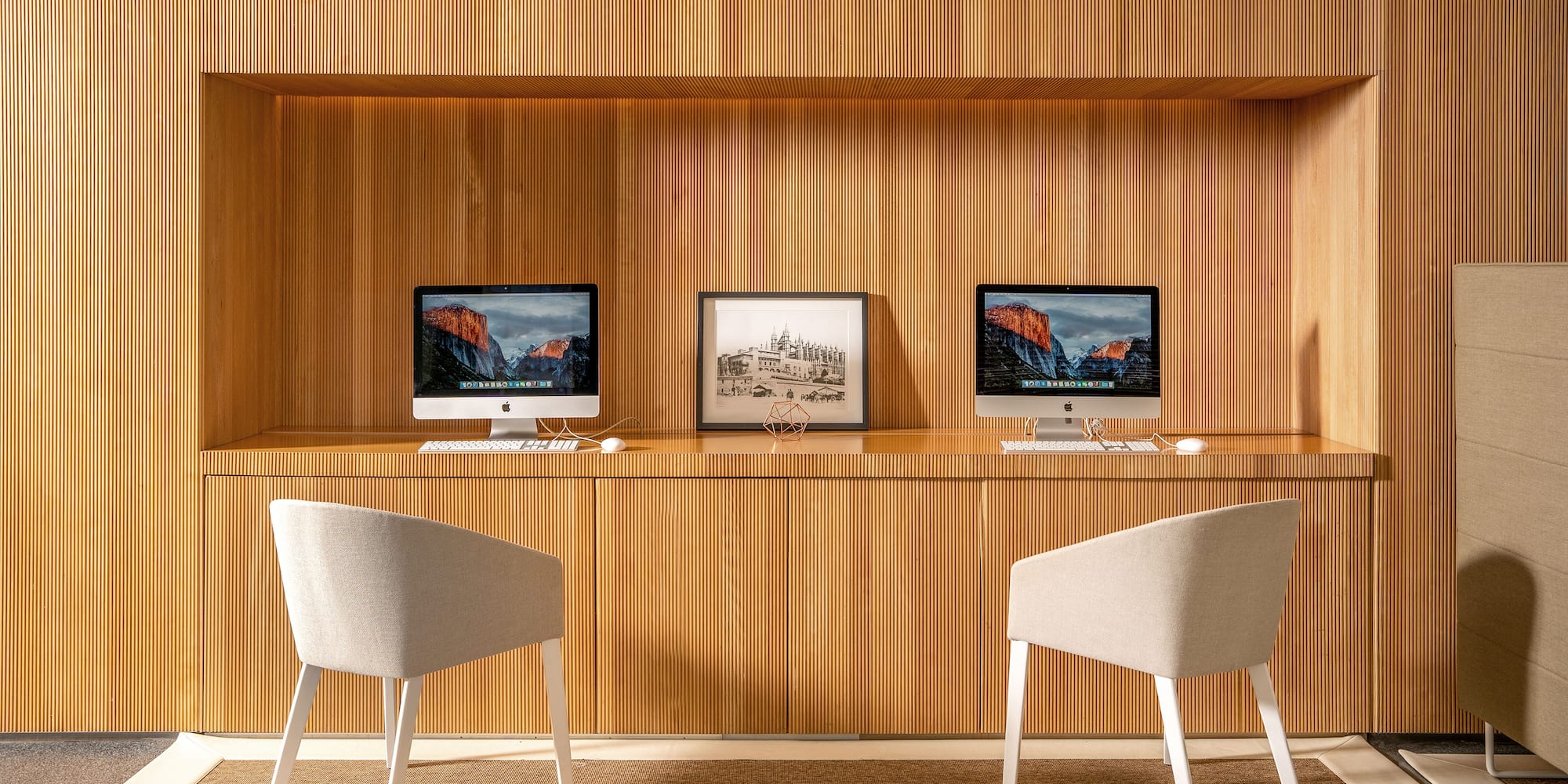 a desk with two computers and a picture frame on it