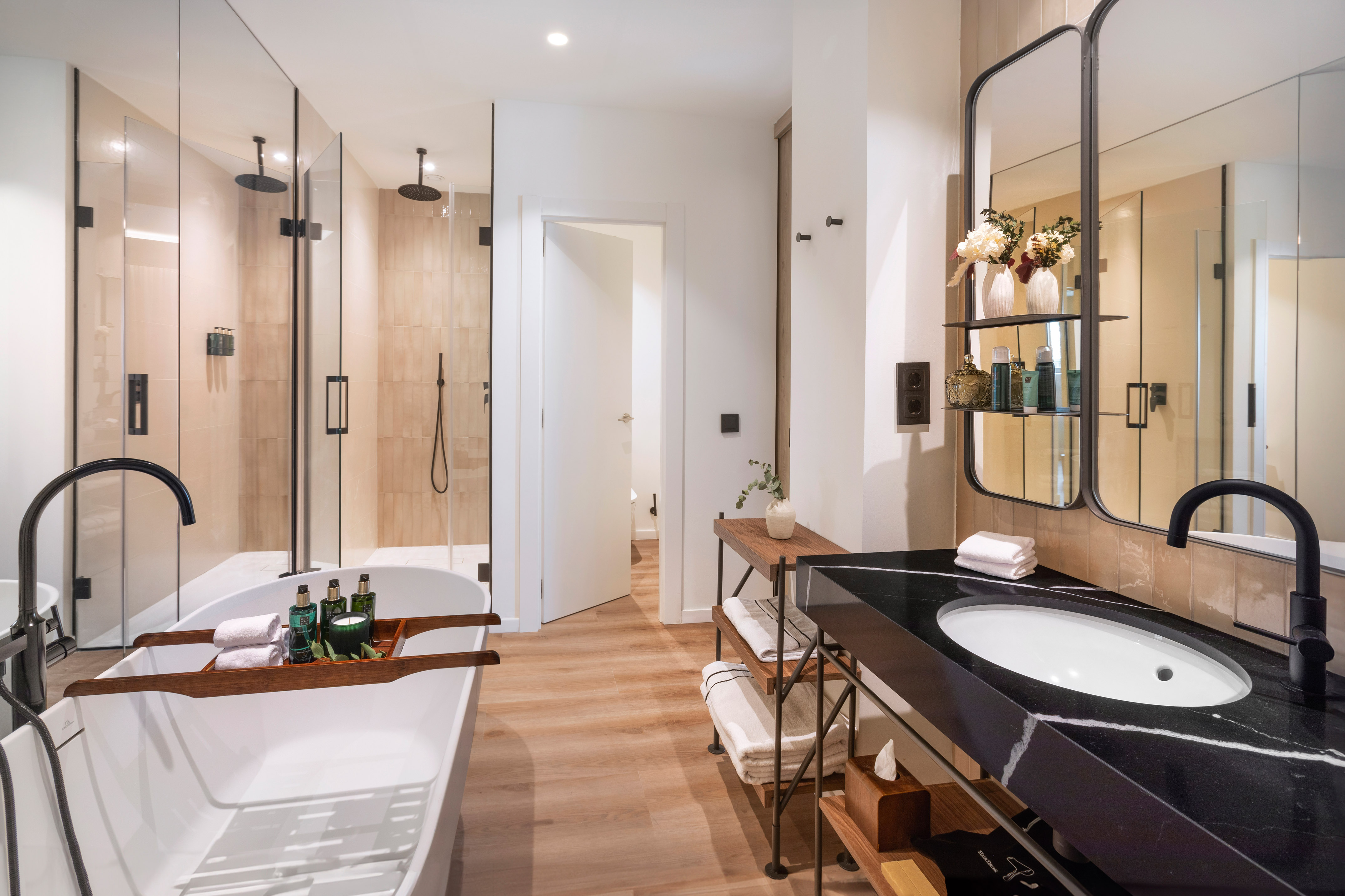 Luxury modern bathroom with freestanding tub, glass shower, and black vanity.