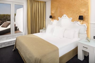 a bed with white sheets and gold accents