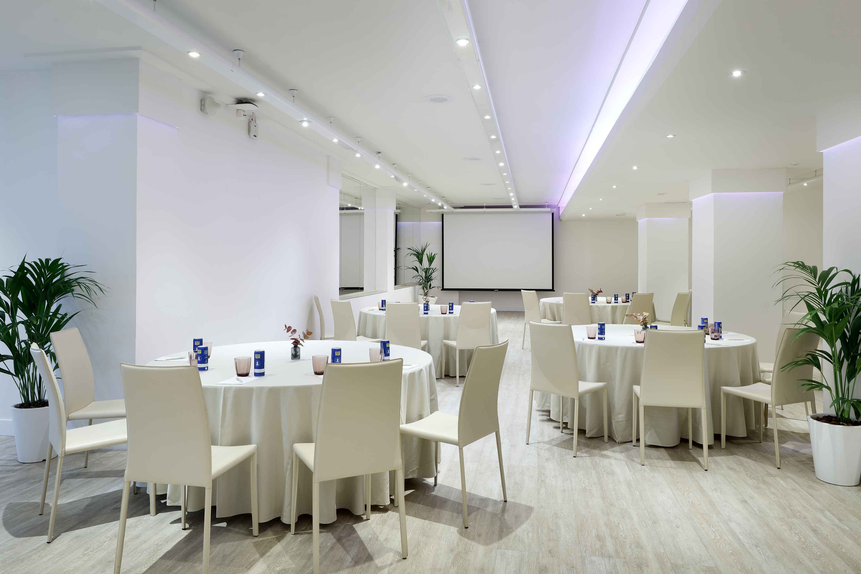 Conference room with round tables, white chairs, and a projection screen.