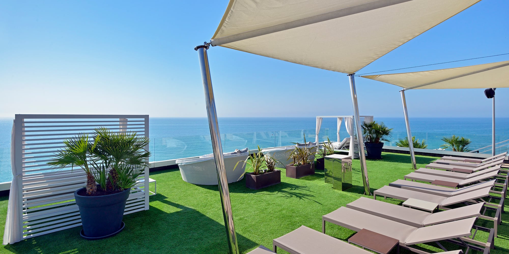 a deck with chairs and a large white canopy on a green lawn