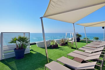 a deck with chairs and a large white canopy on a green lawn