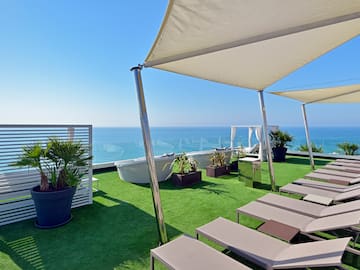 a deck with chairs and a large white canopy on a green lawn