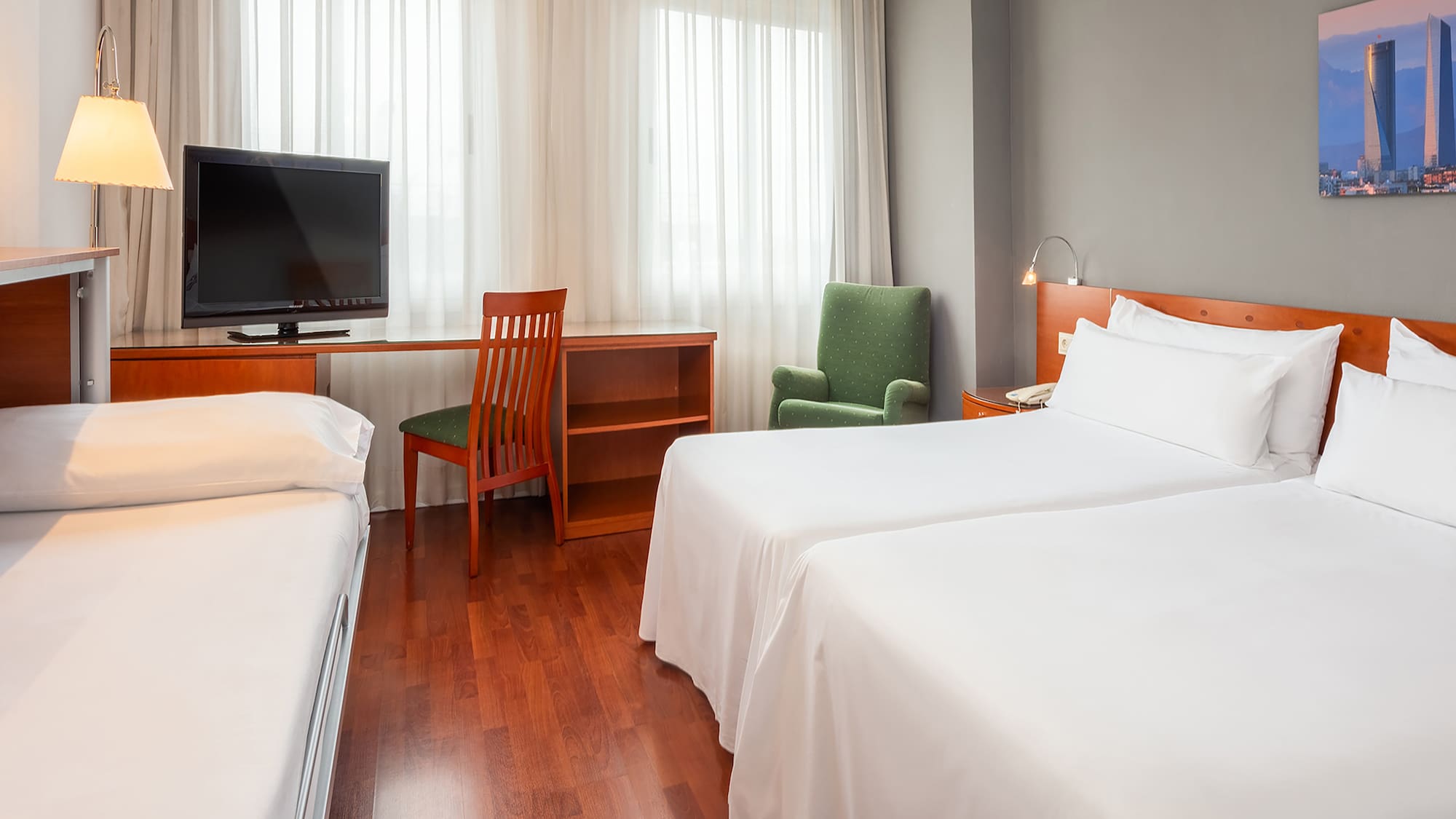 Triple hotel room with two twin beds, extra cot, desk, and TV.