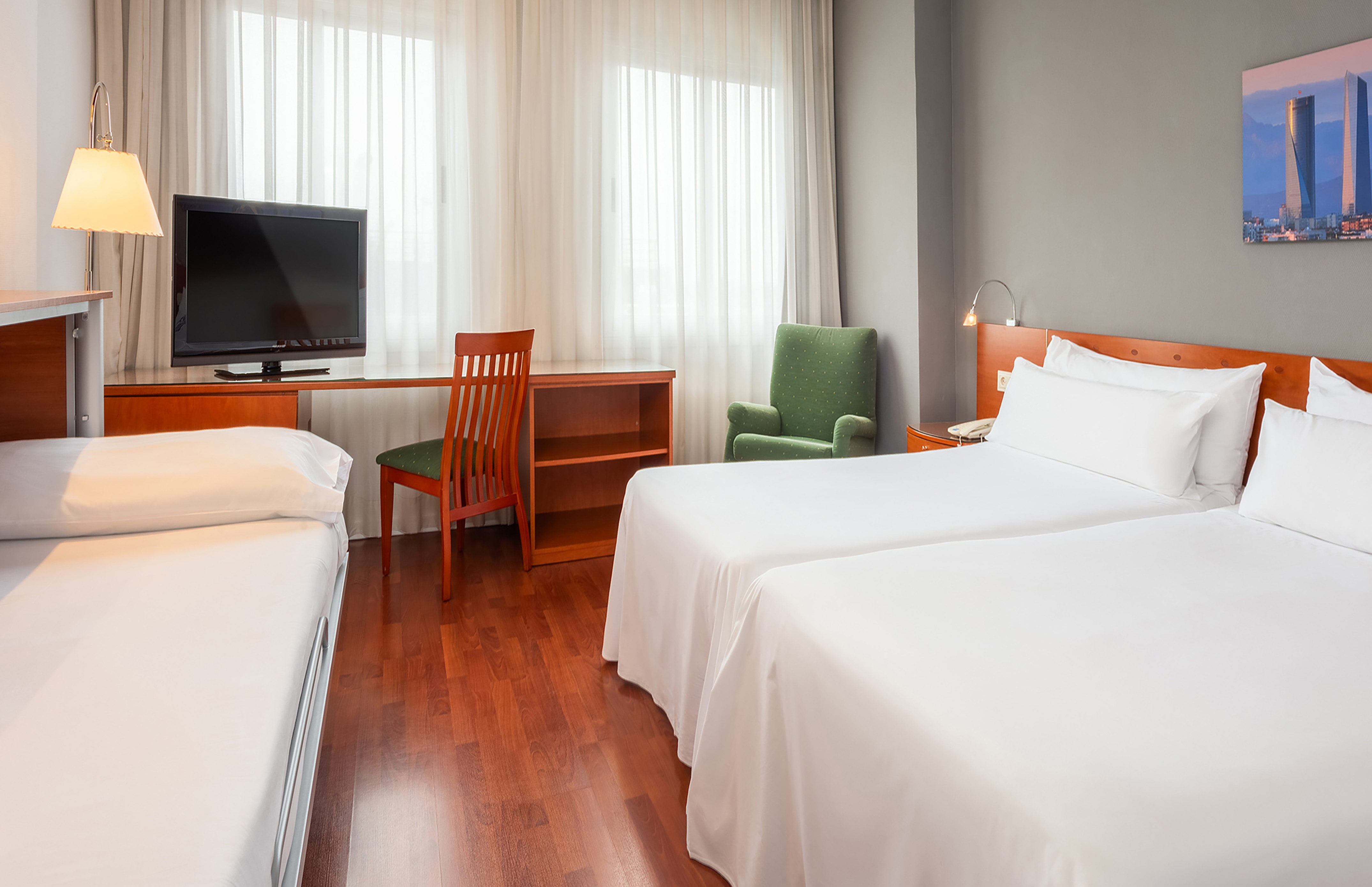 Triple hotel room with two twin beds, extra cot, desk, and TV.