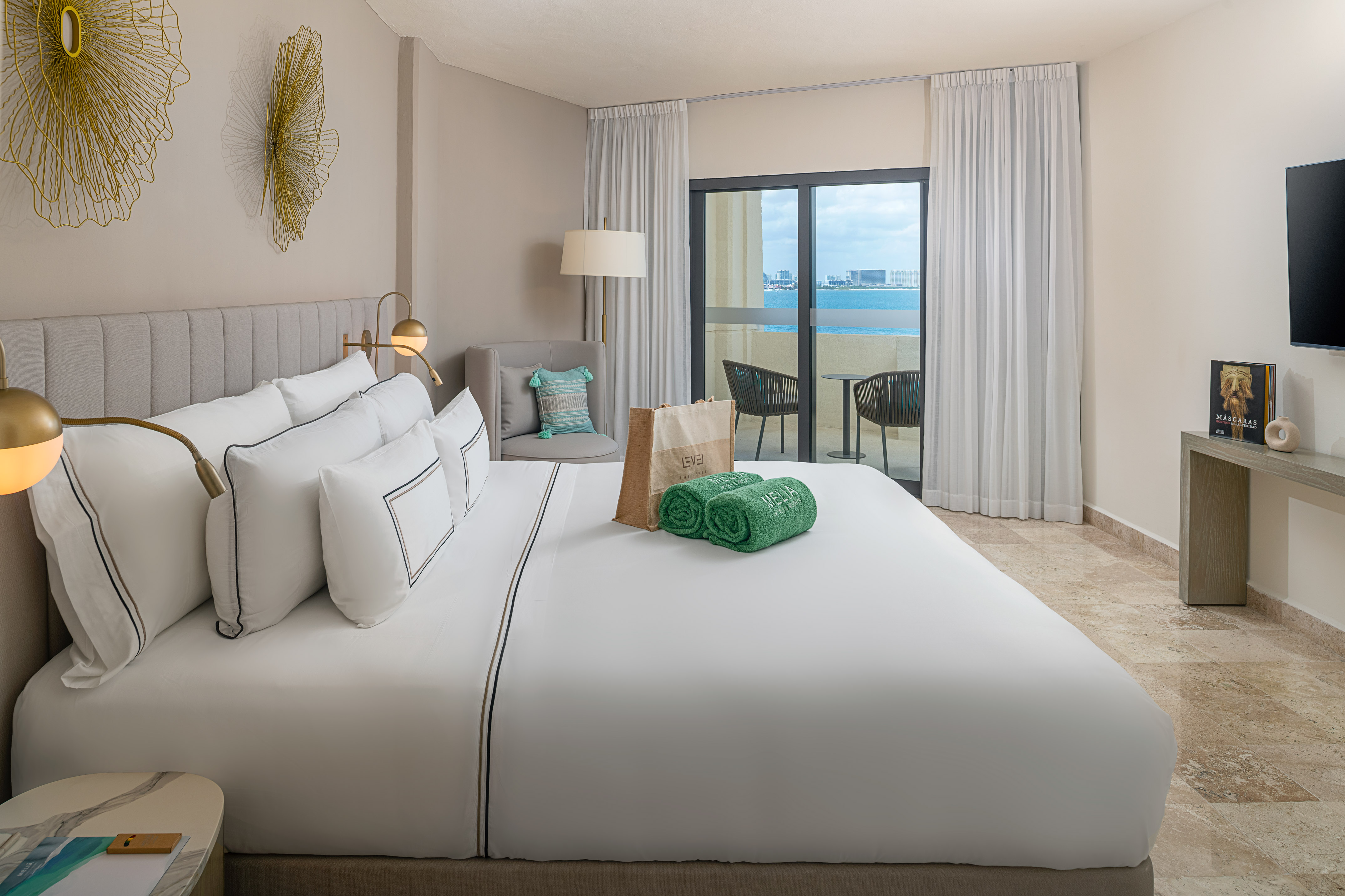 Modern hotel room with king bed, ocean view balcony, and contemporary decor.
