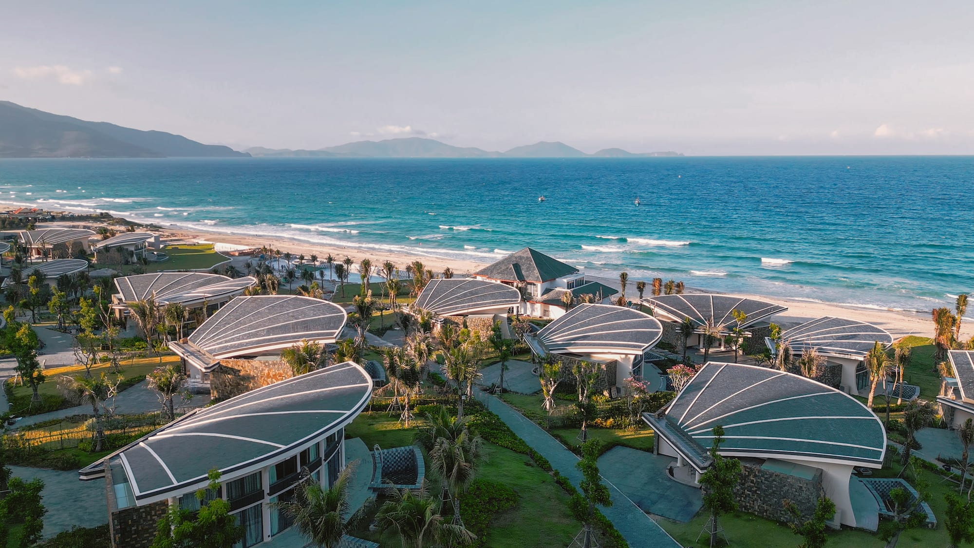 Modern resort with shell-shaped roofs, beachfront villas, and blue ocean.