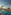 Luxury resort pool with palm trees, sun loungers, beach, and ocean.