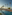 Luxury resort pool with palm trees, sun loungers, beach, and ocean.