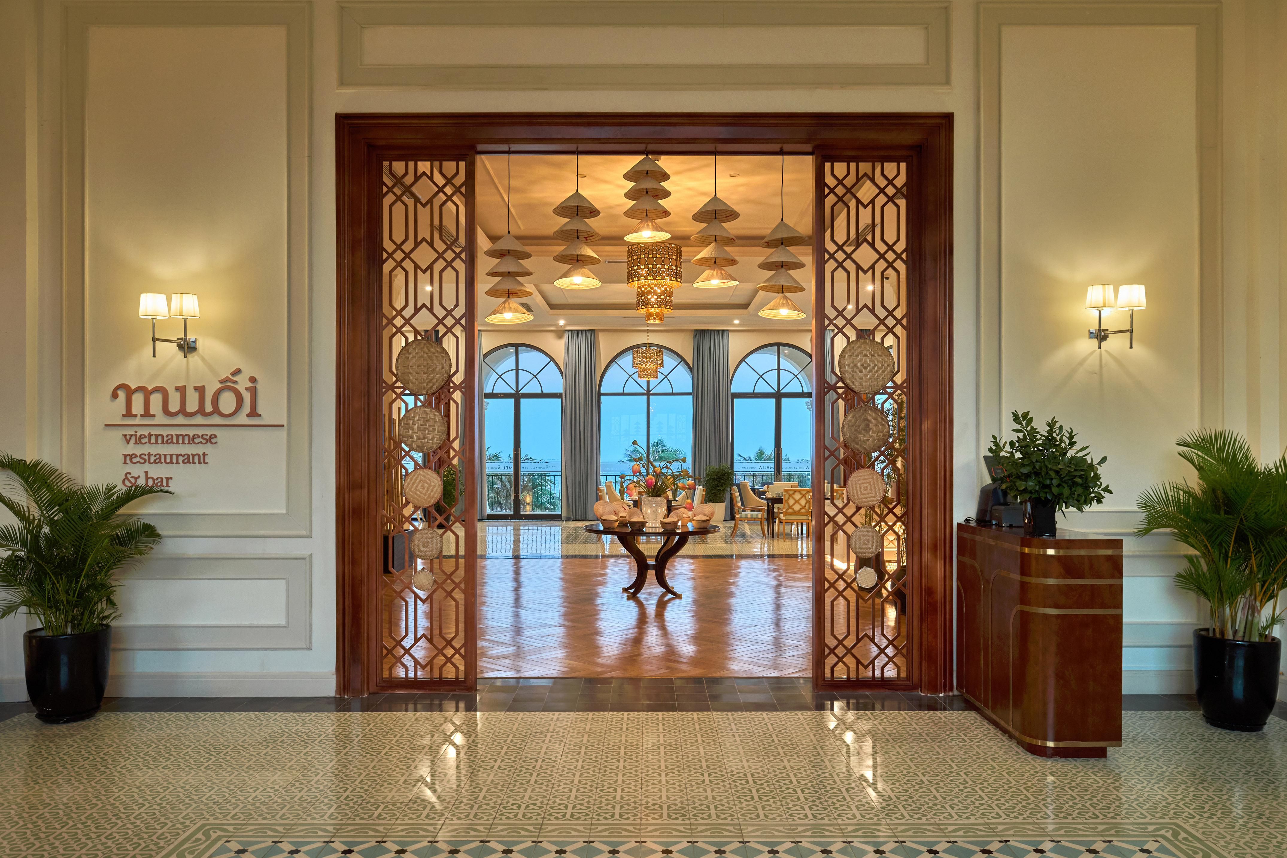 Muoi Vietnamese restaurant & bar entrance with elegant decor, arched windows.