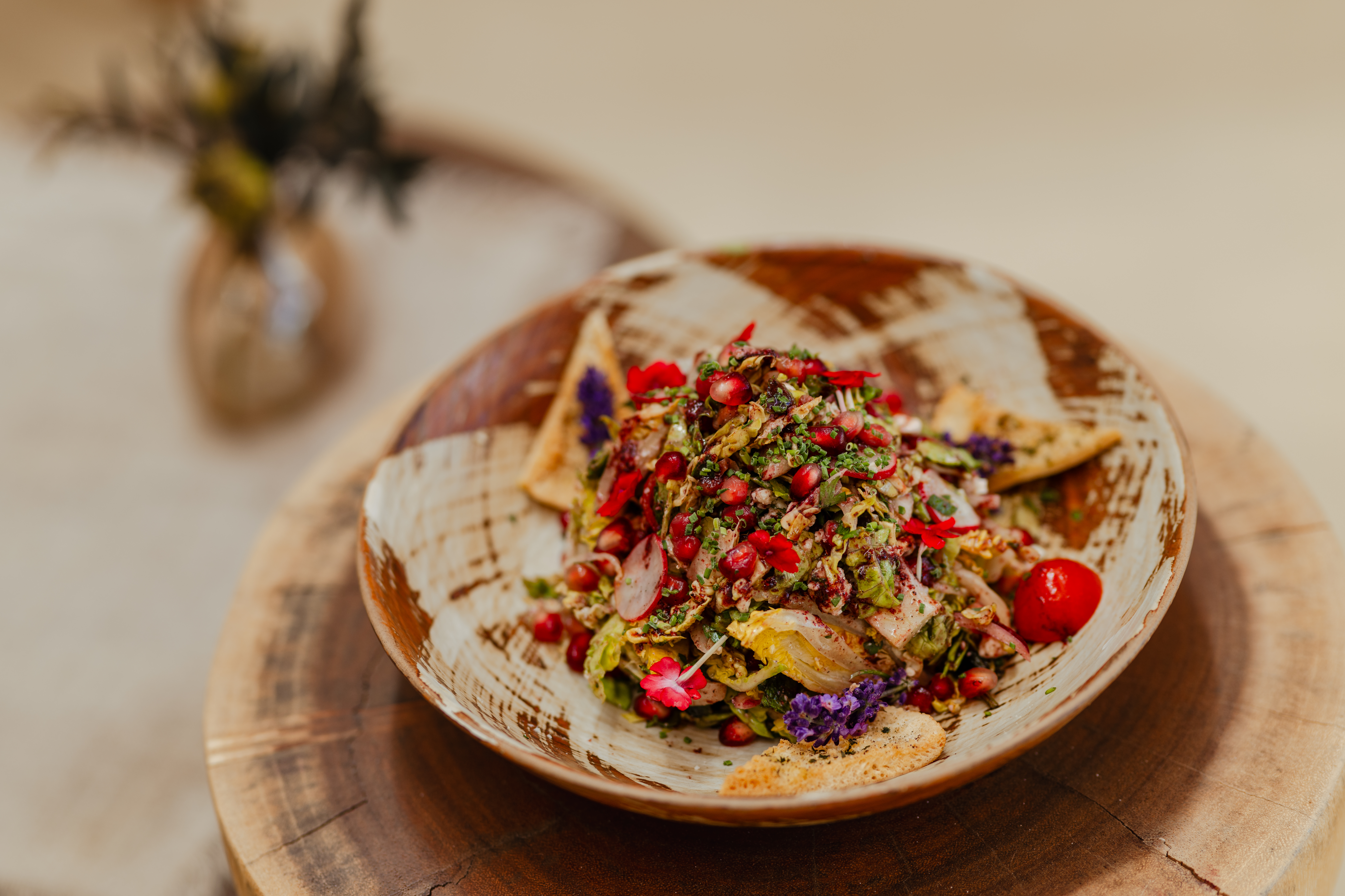 Vibrant pomegranate salad with fresh greens, edible flowers, and flatbread.