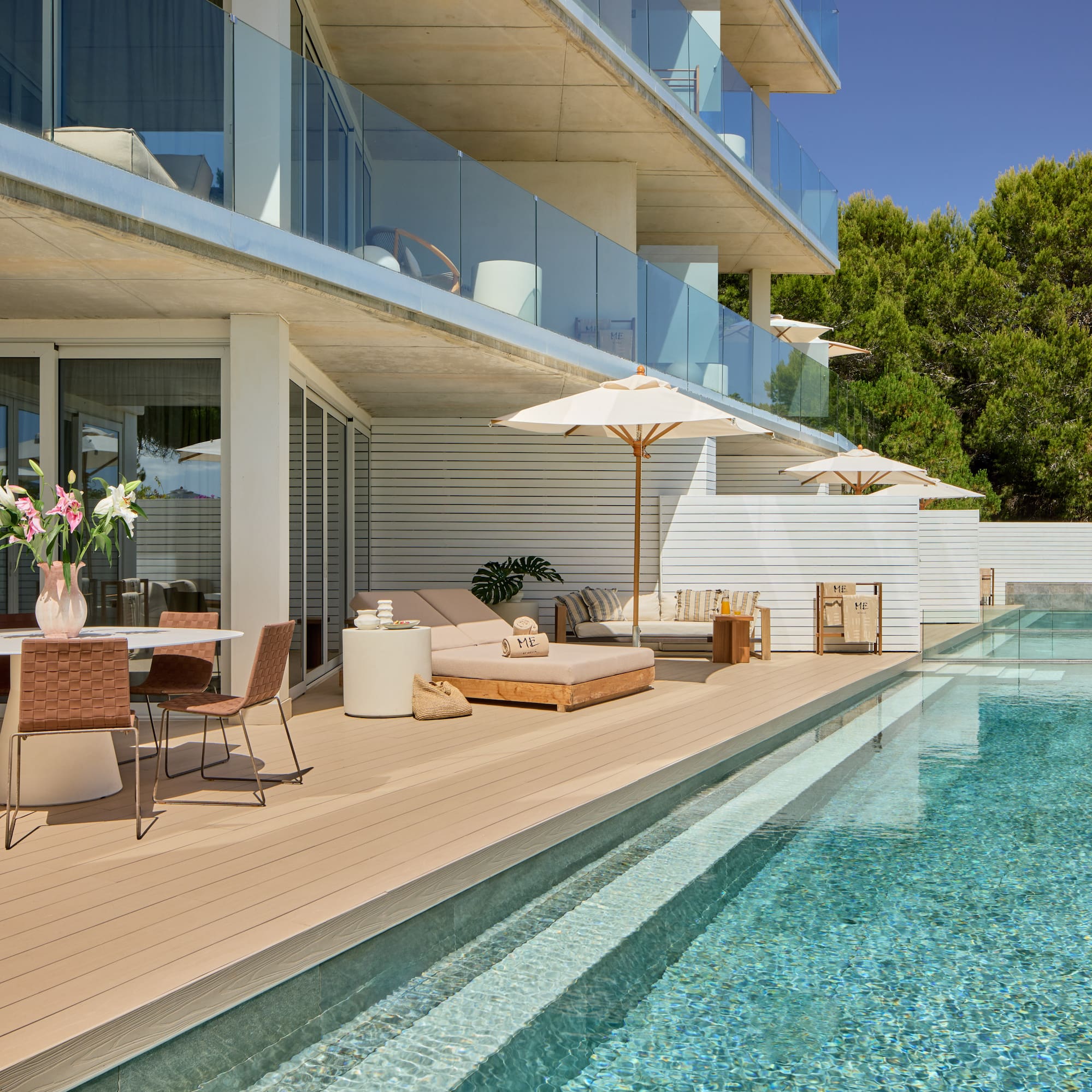 Modern resort terrace with pool, dining, and sun loungers under balconies.
