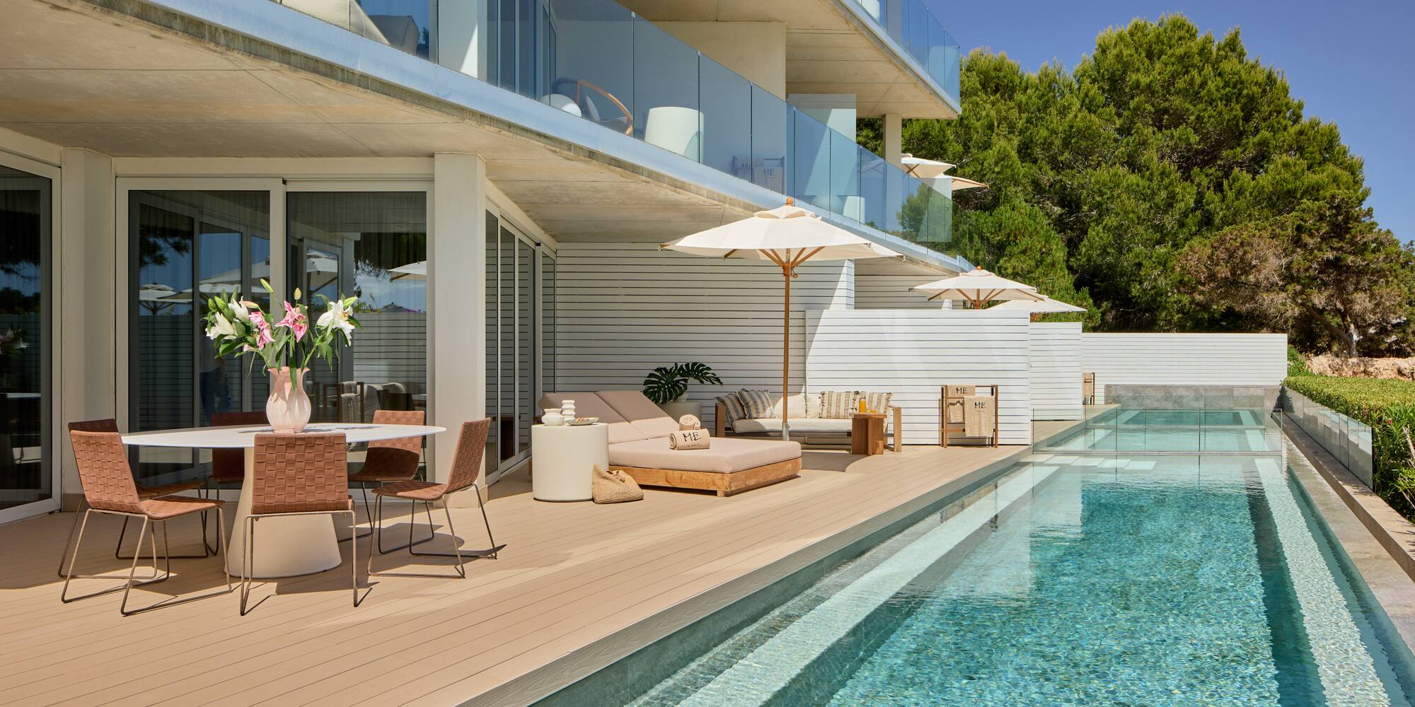 Modern resort terrace with pool, dining, and sun loungers under balconies.