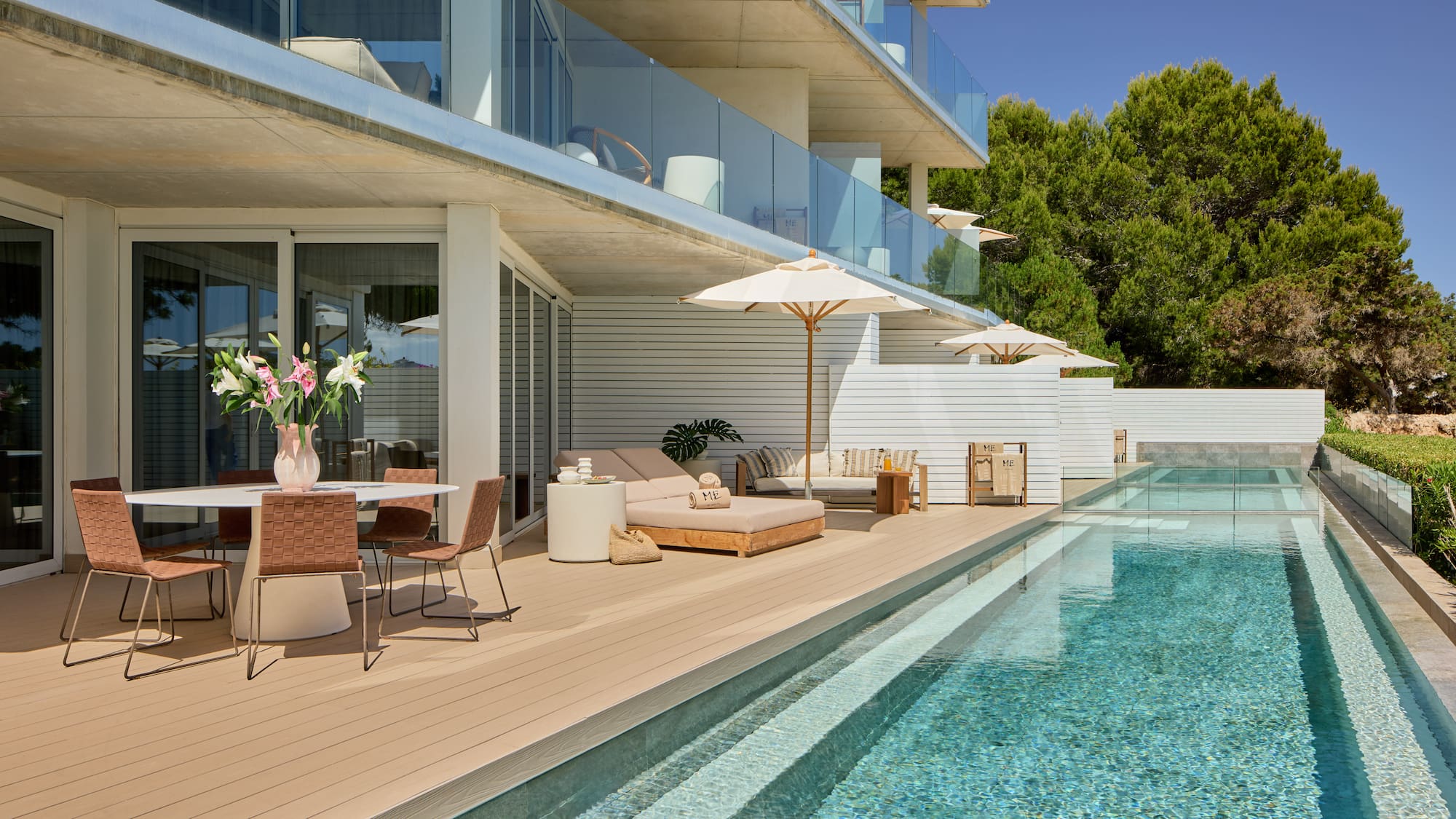Modern resort terrace with pool, dining, and sun loungers under balconies.