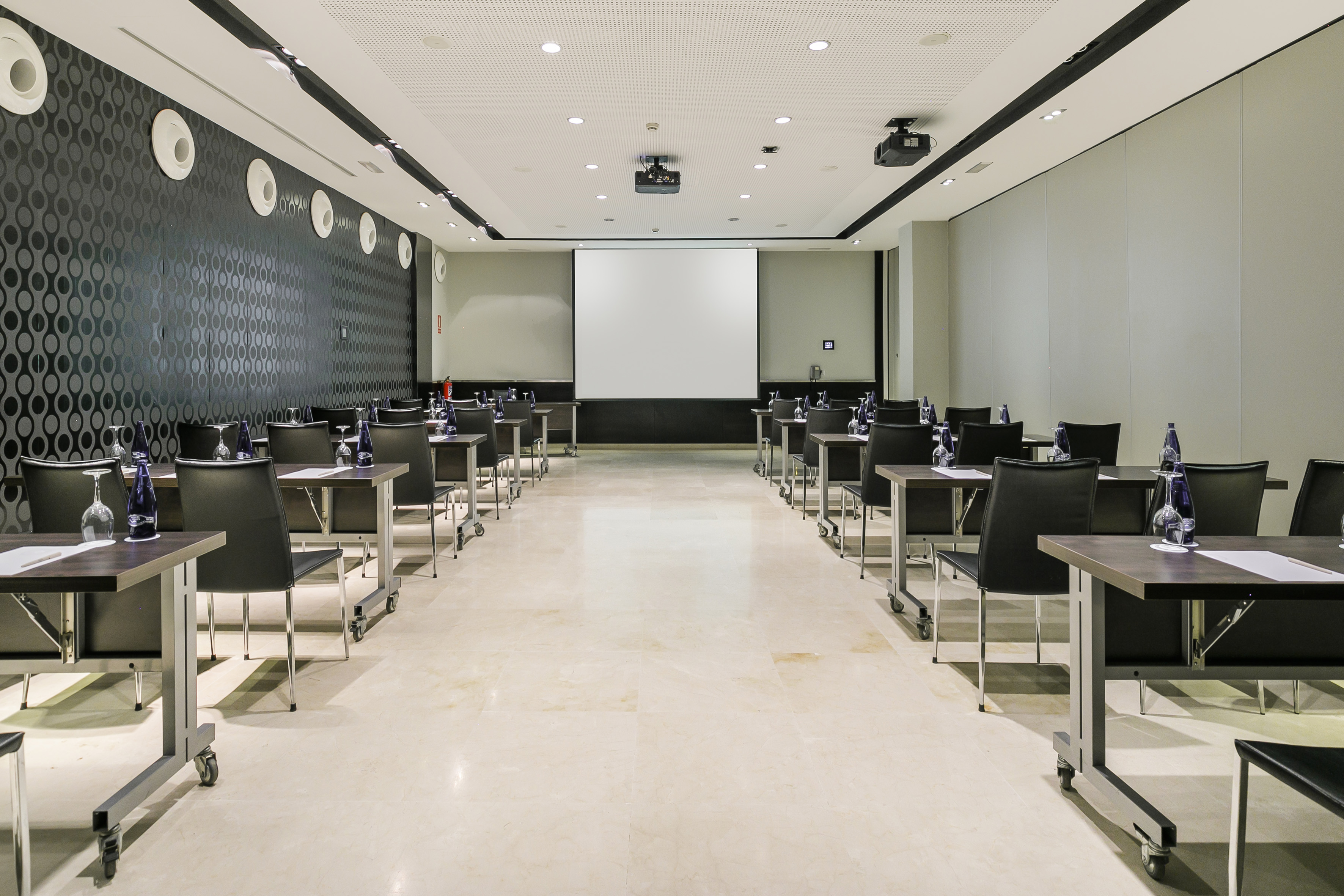 Professional meeting room with projector screen, tables, and chairs.