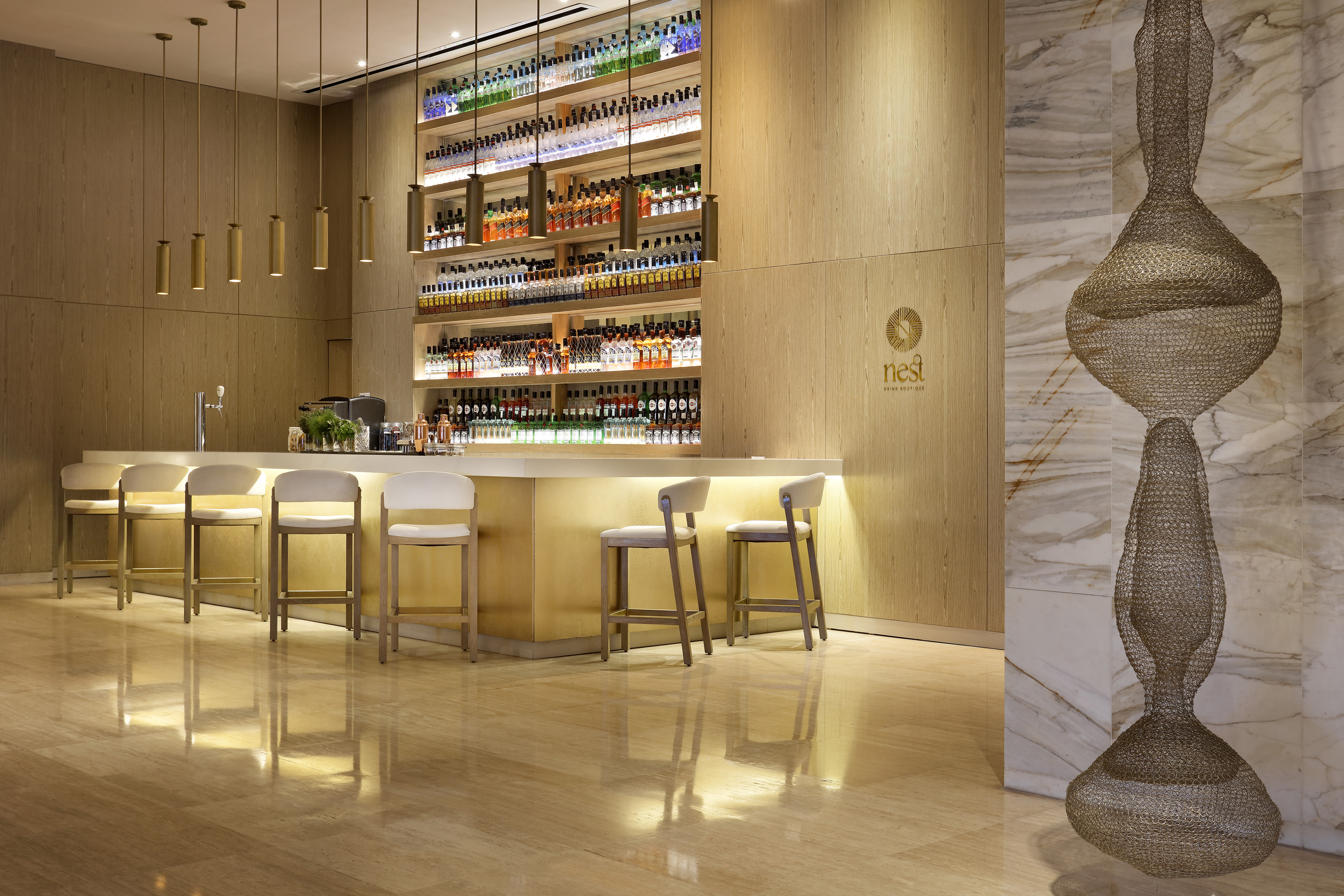Modern Nest Drink Boutique bar with backlit liquor bottles and sleek bar stools.