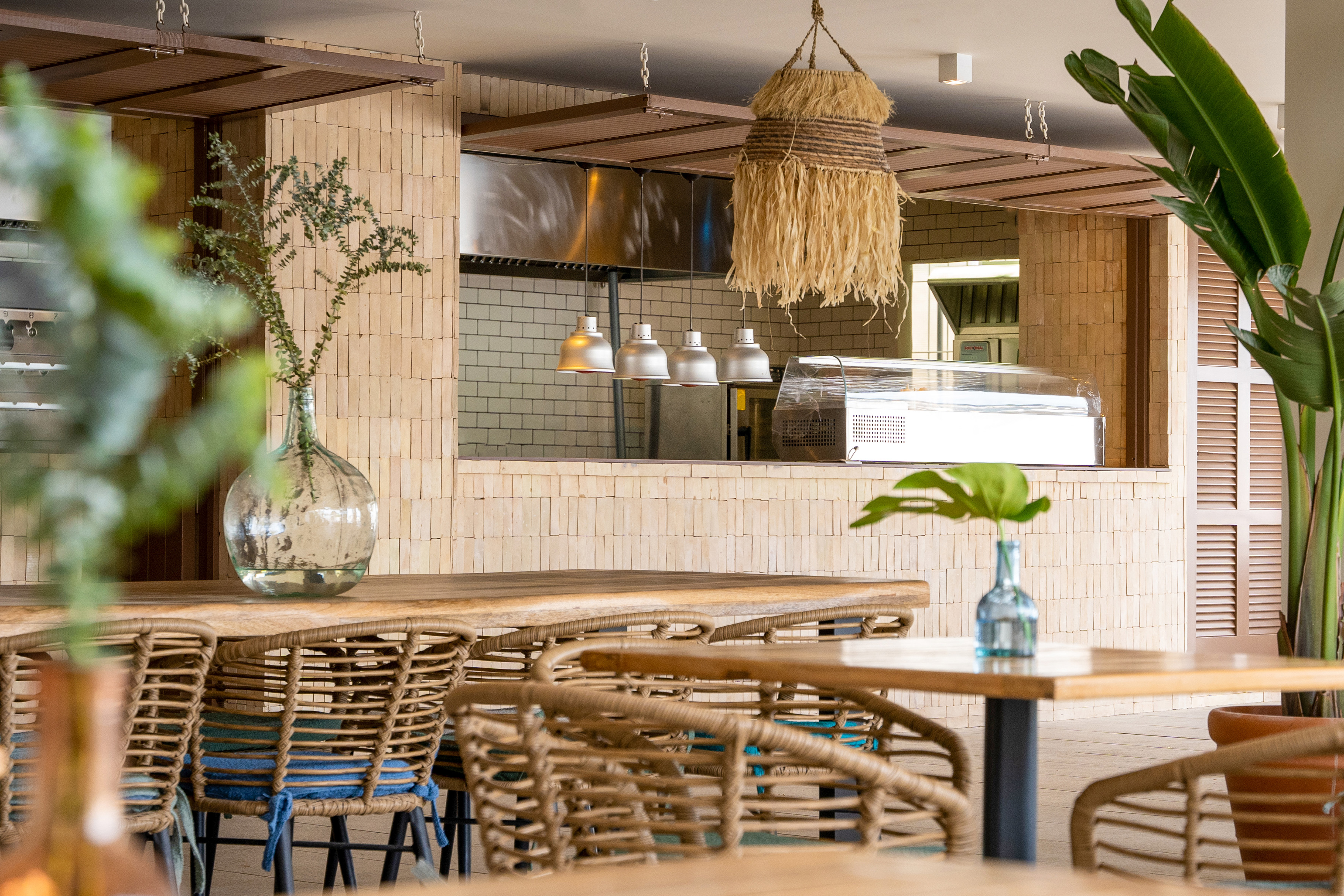 Rattan chairs, wooden tables, and brick counter in a tropical restaurant.