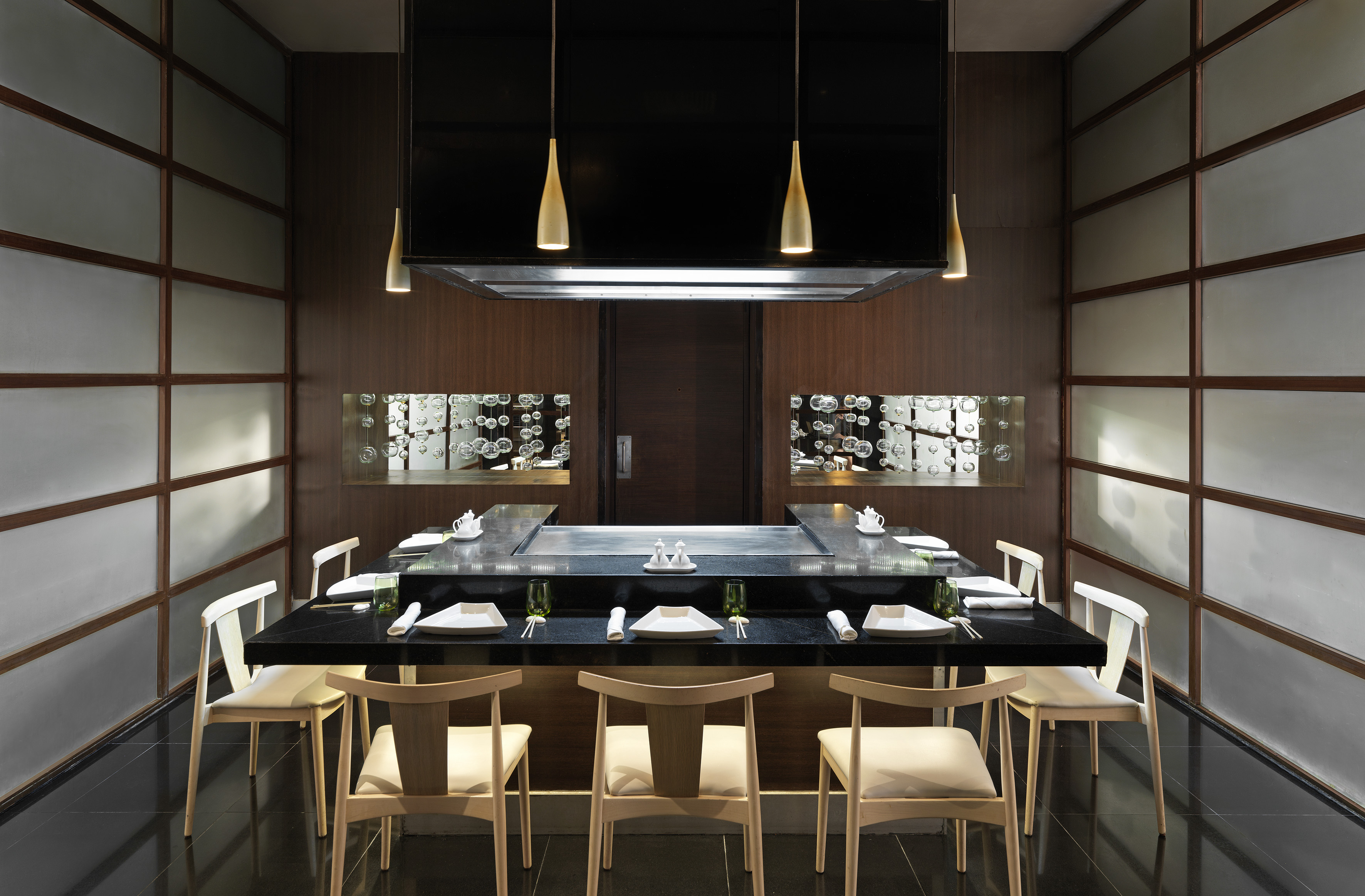 Teppanyaki chef's table with grill, place settings, and modern lighting.
