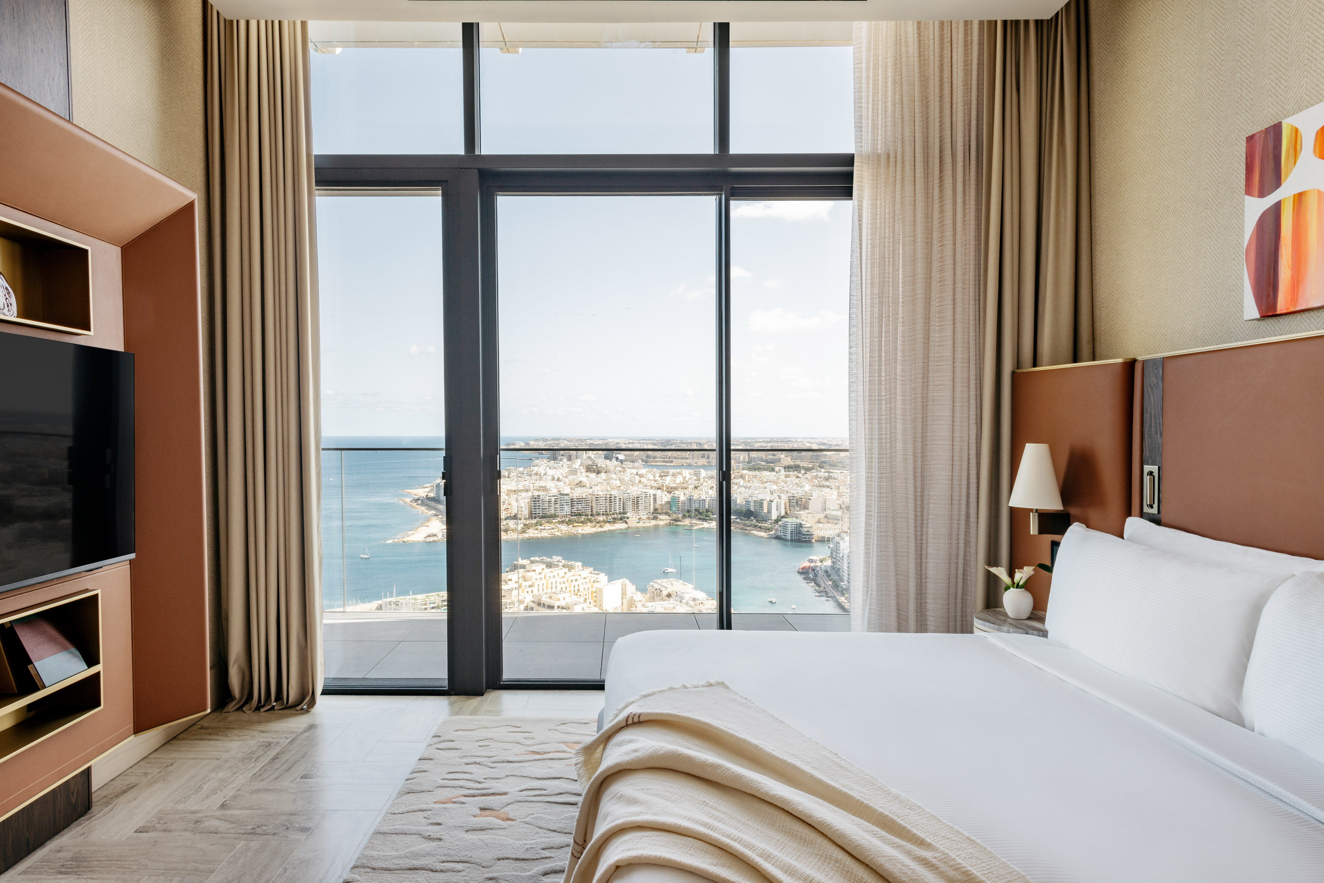 Luxury hotel room with panoramic coastal city and ocean view.