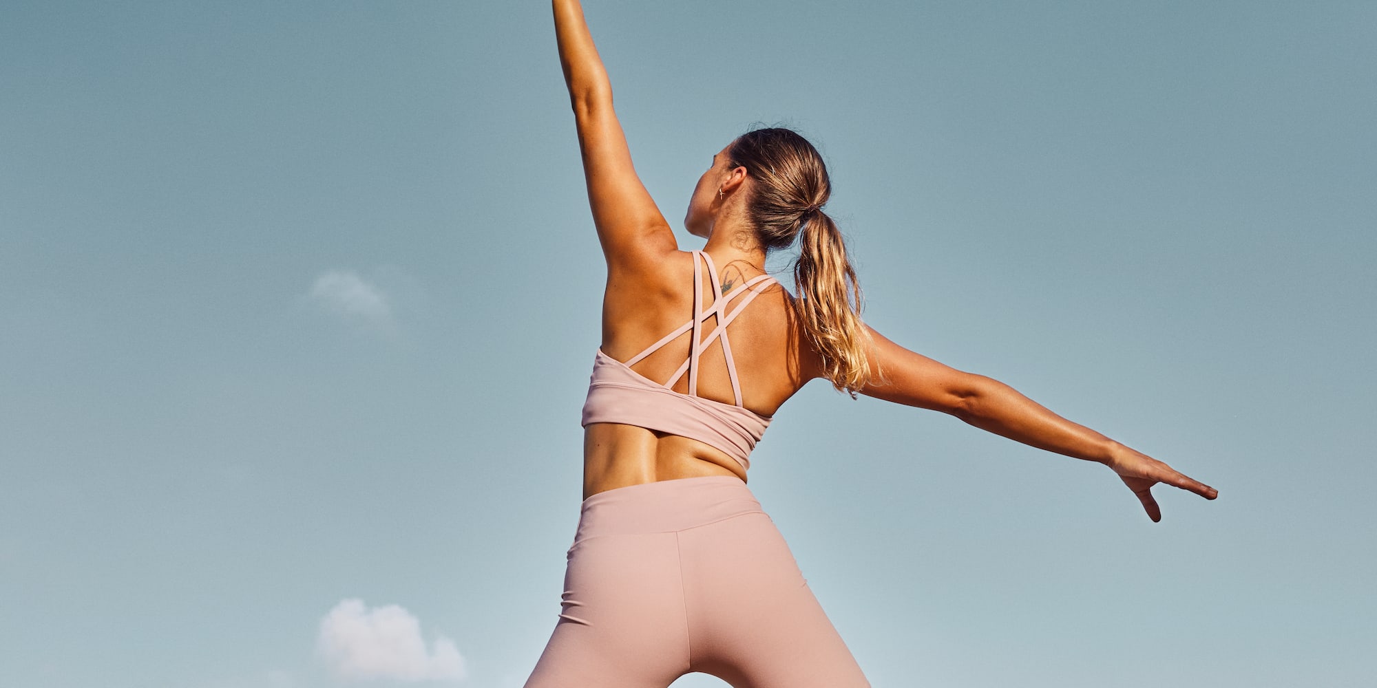a woman in pink outfit with arms outstretched