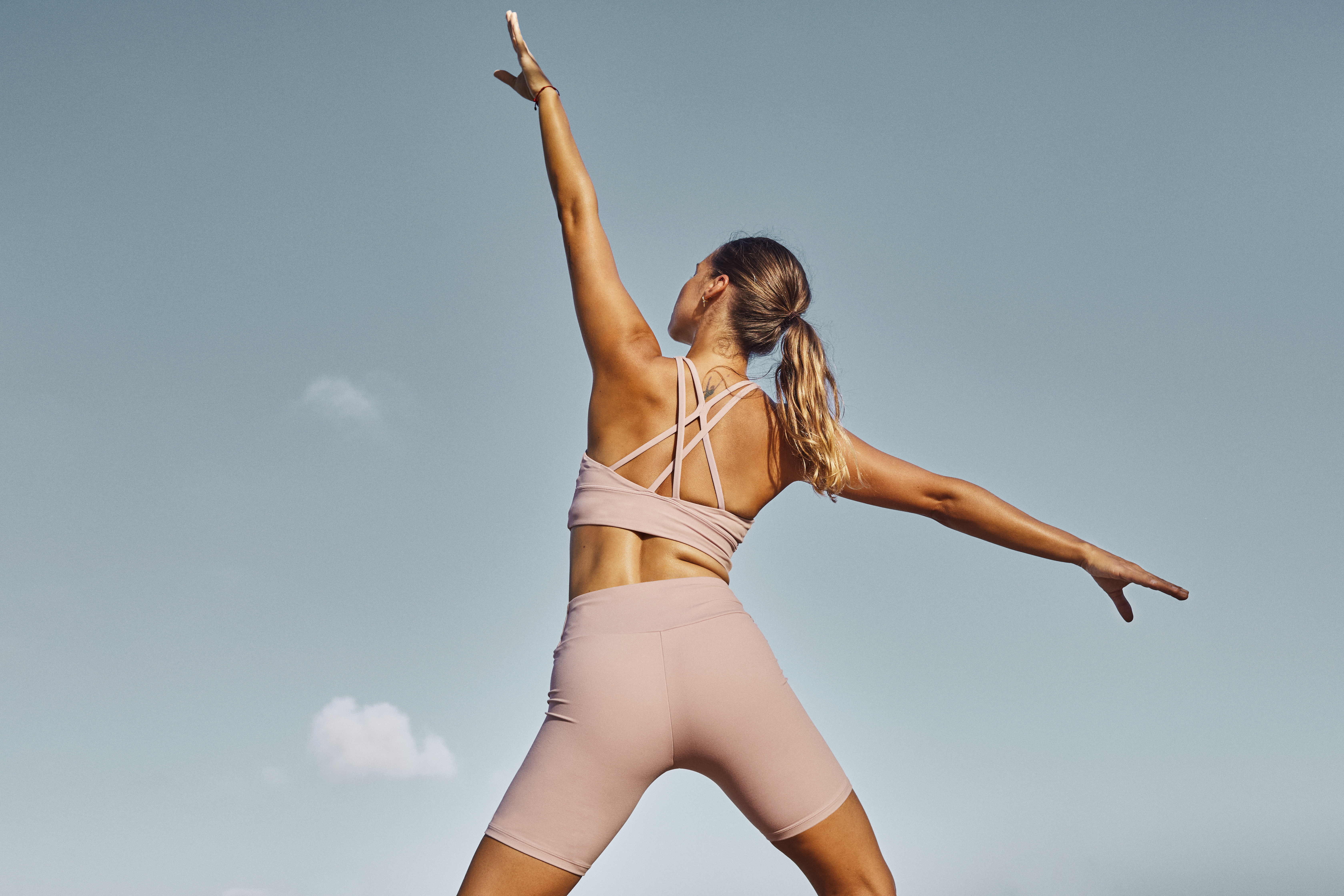 a woman in pink outfit with arms outstretched