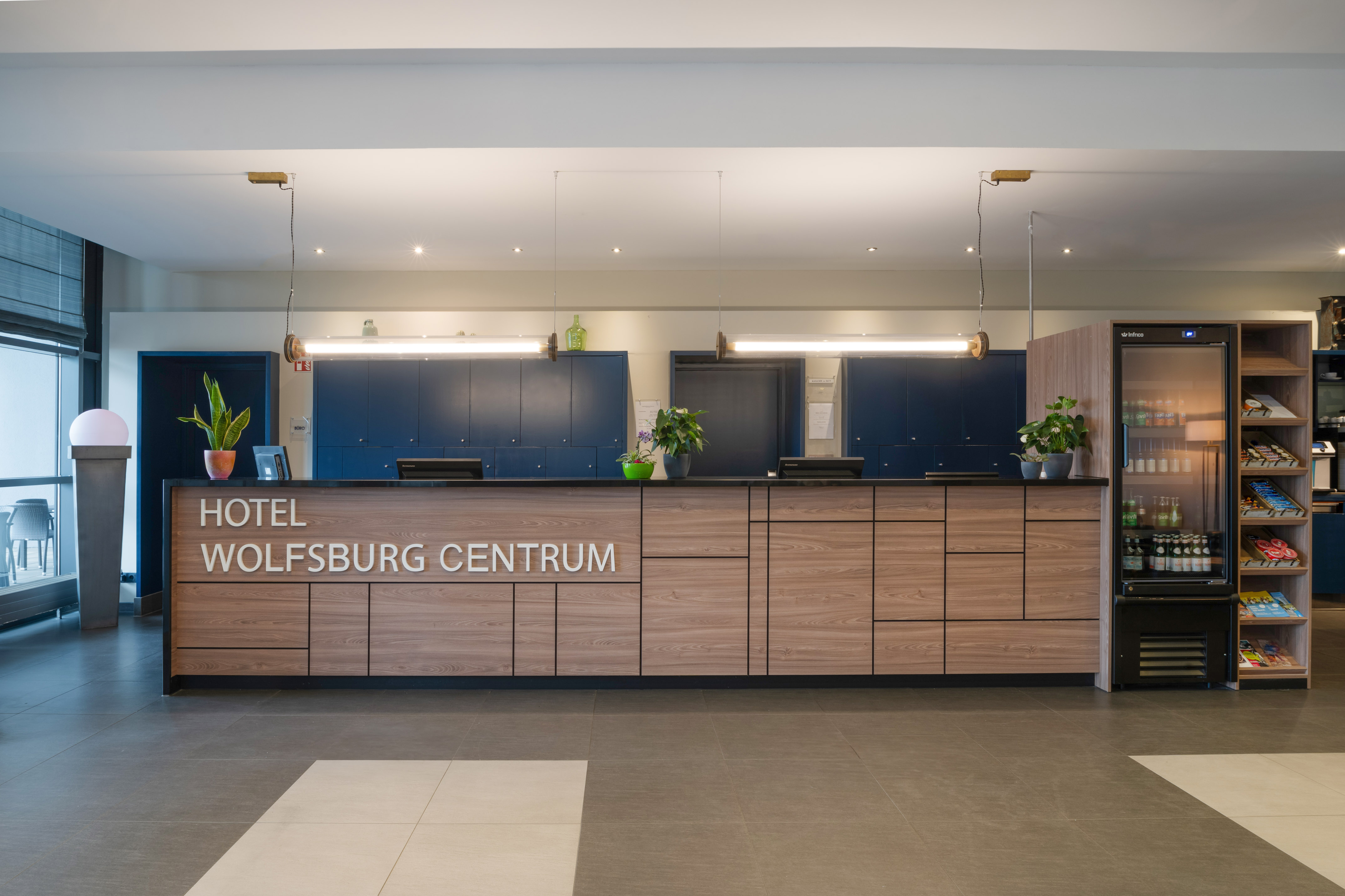 Hotel Wolfsburg Centrum reception desk, modern wood design with plants.