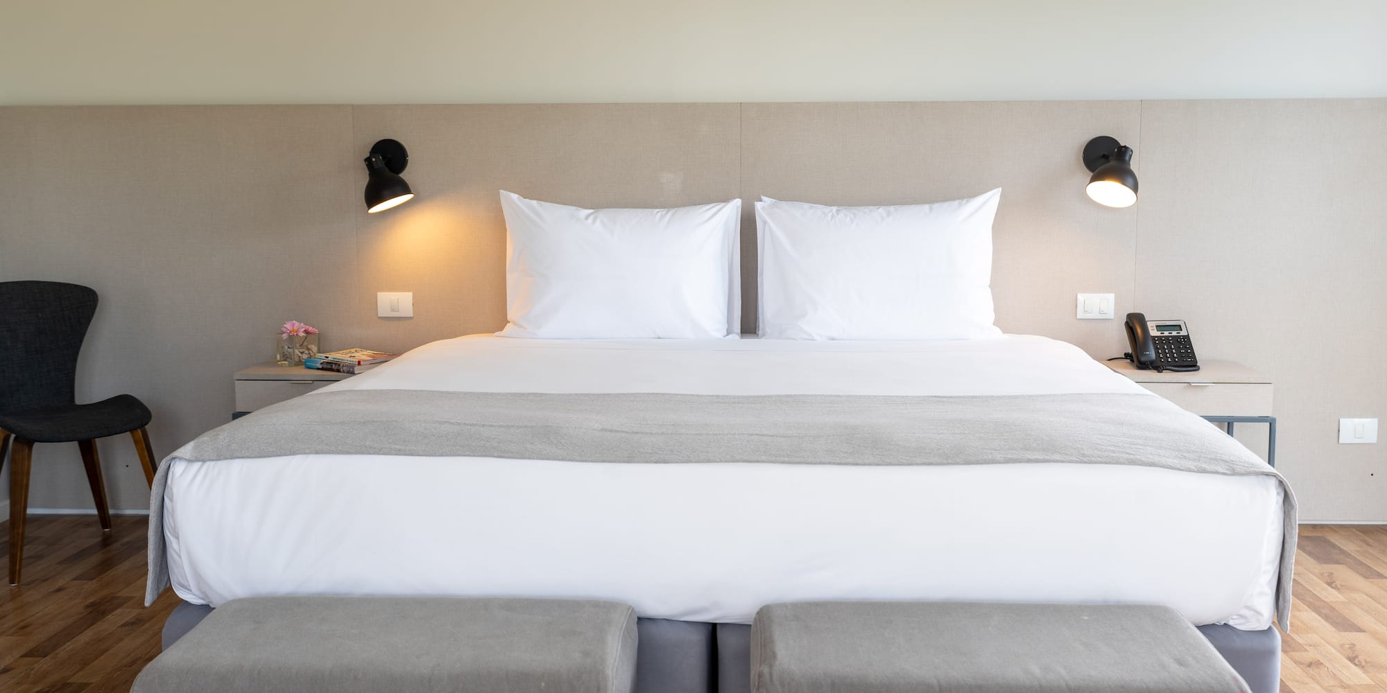 a bed with two pillows and a lamp on the wall