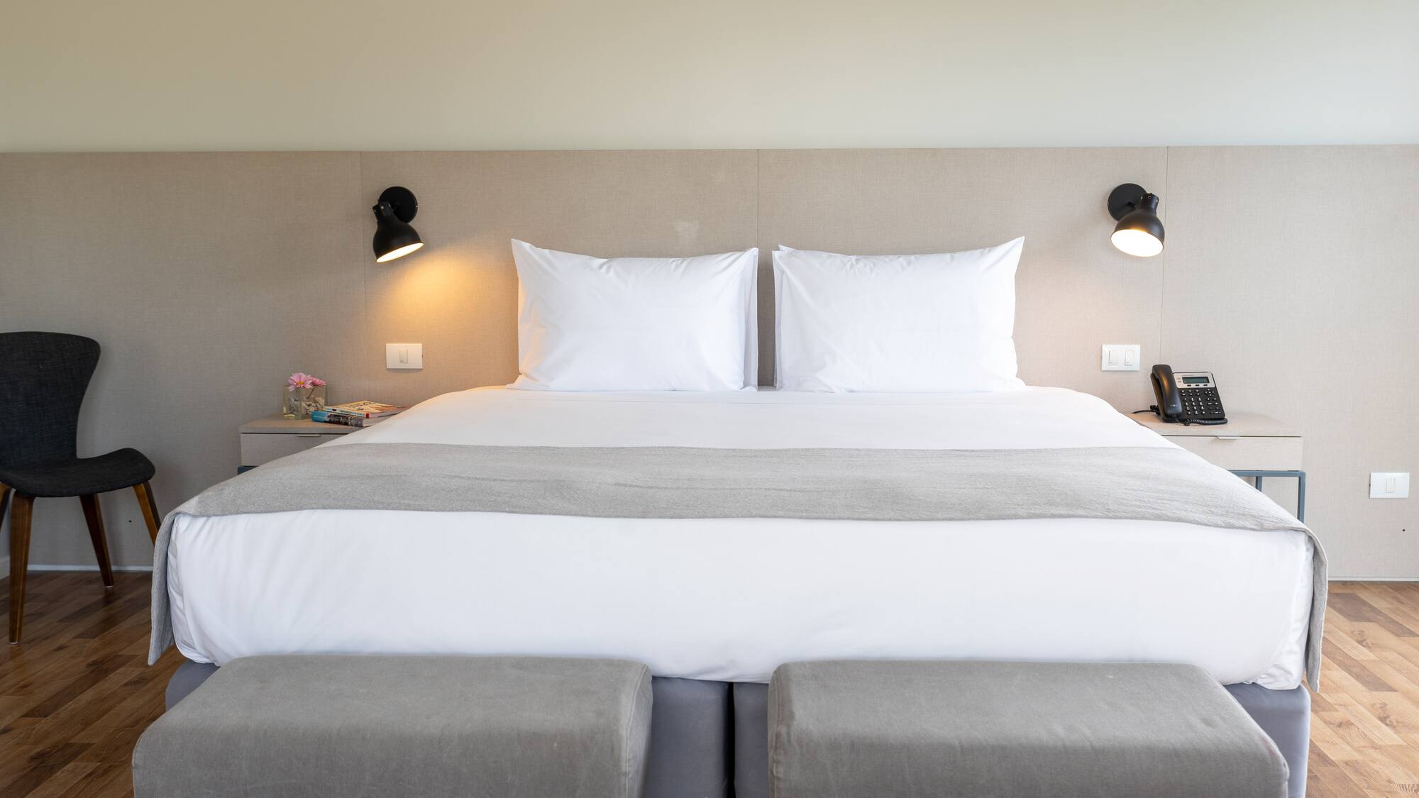 a bed with two pillows and a lamp on the wall