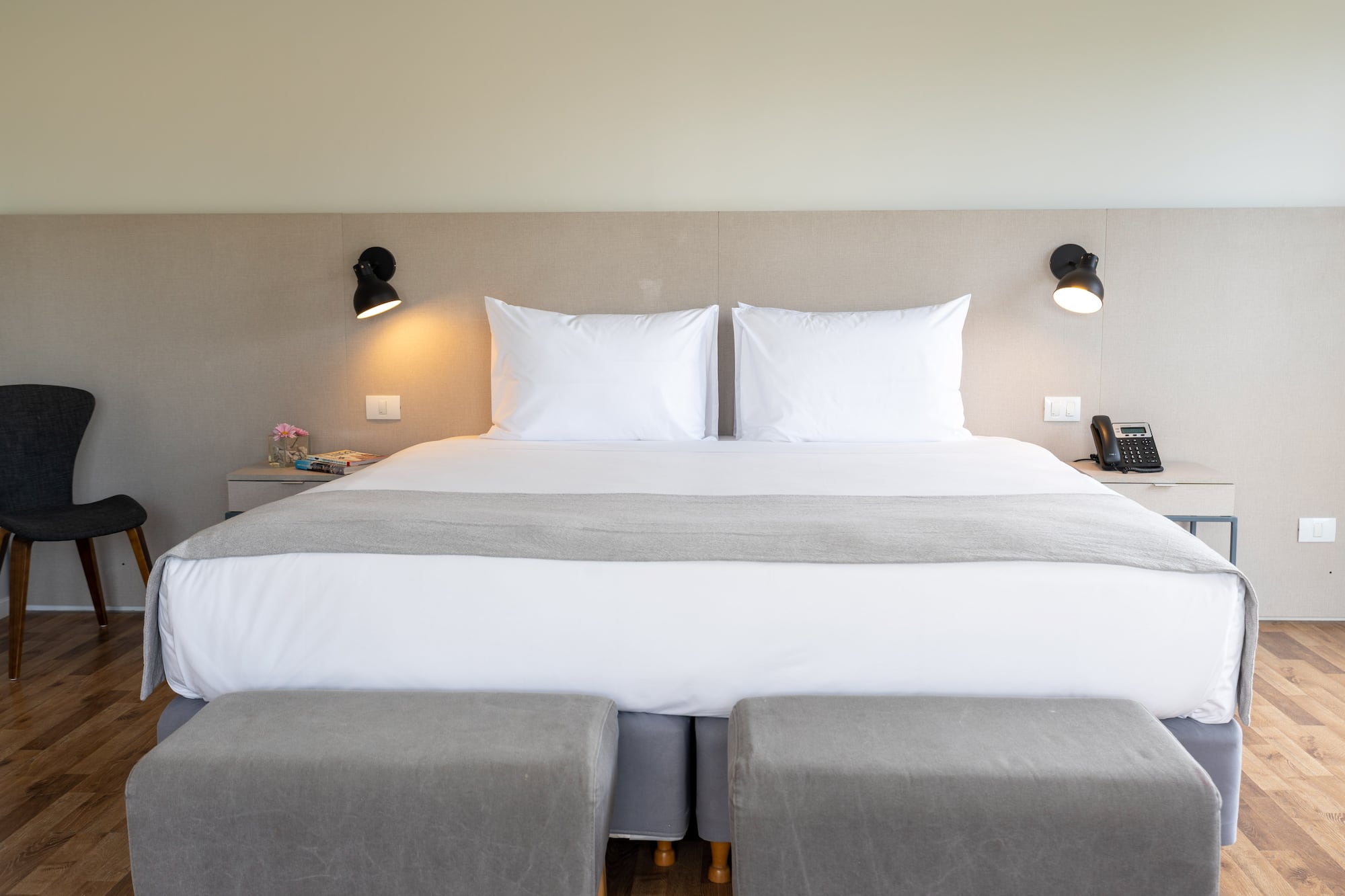 a bed with two pillows and a lamp on the wall