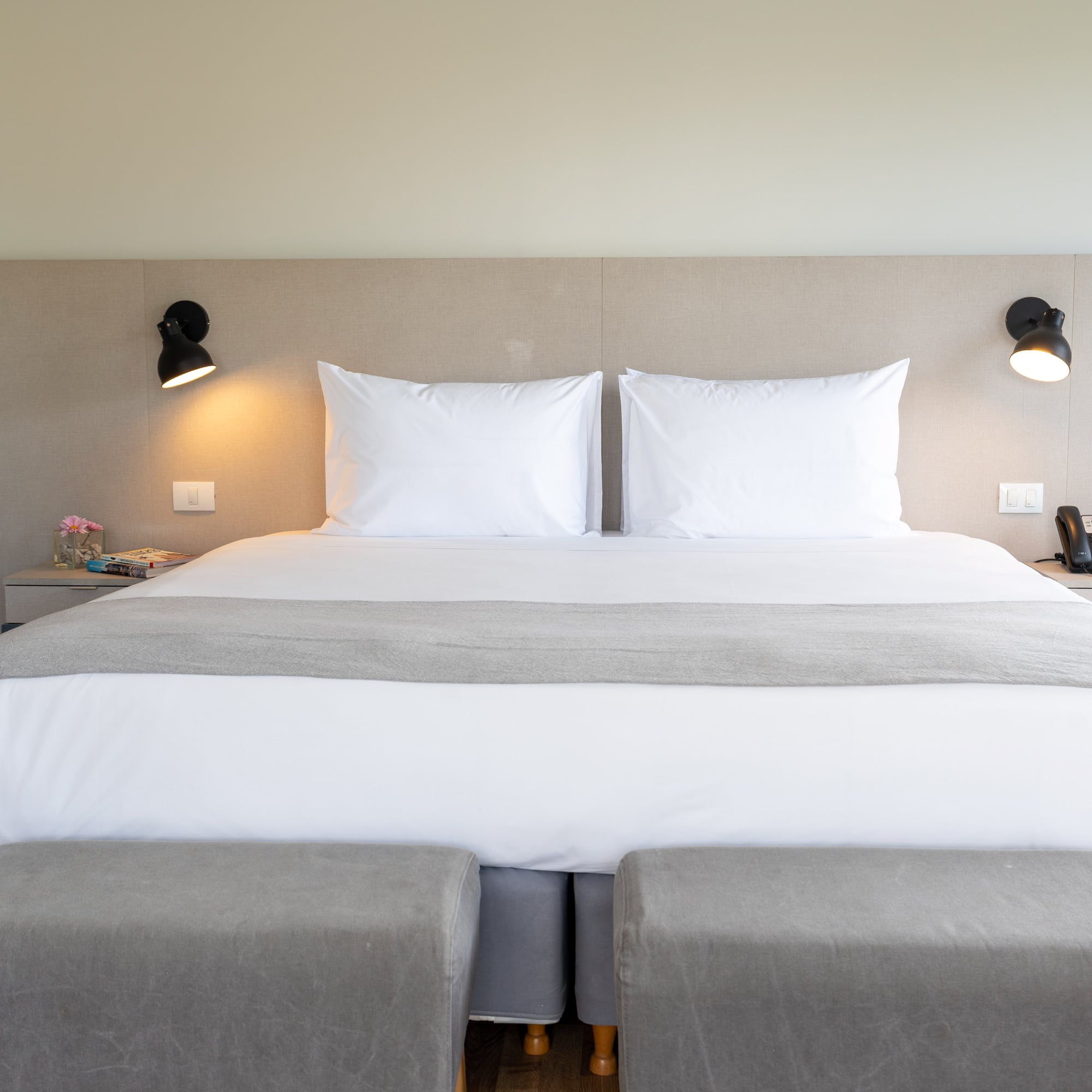 a bed with two pillows and a lamp on the wall