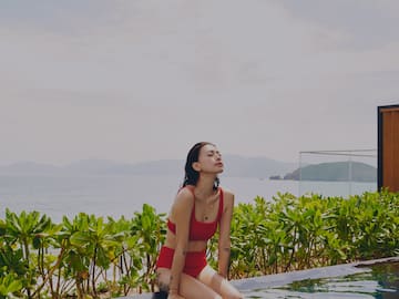 a woman sitting on a pool with water in the background