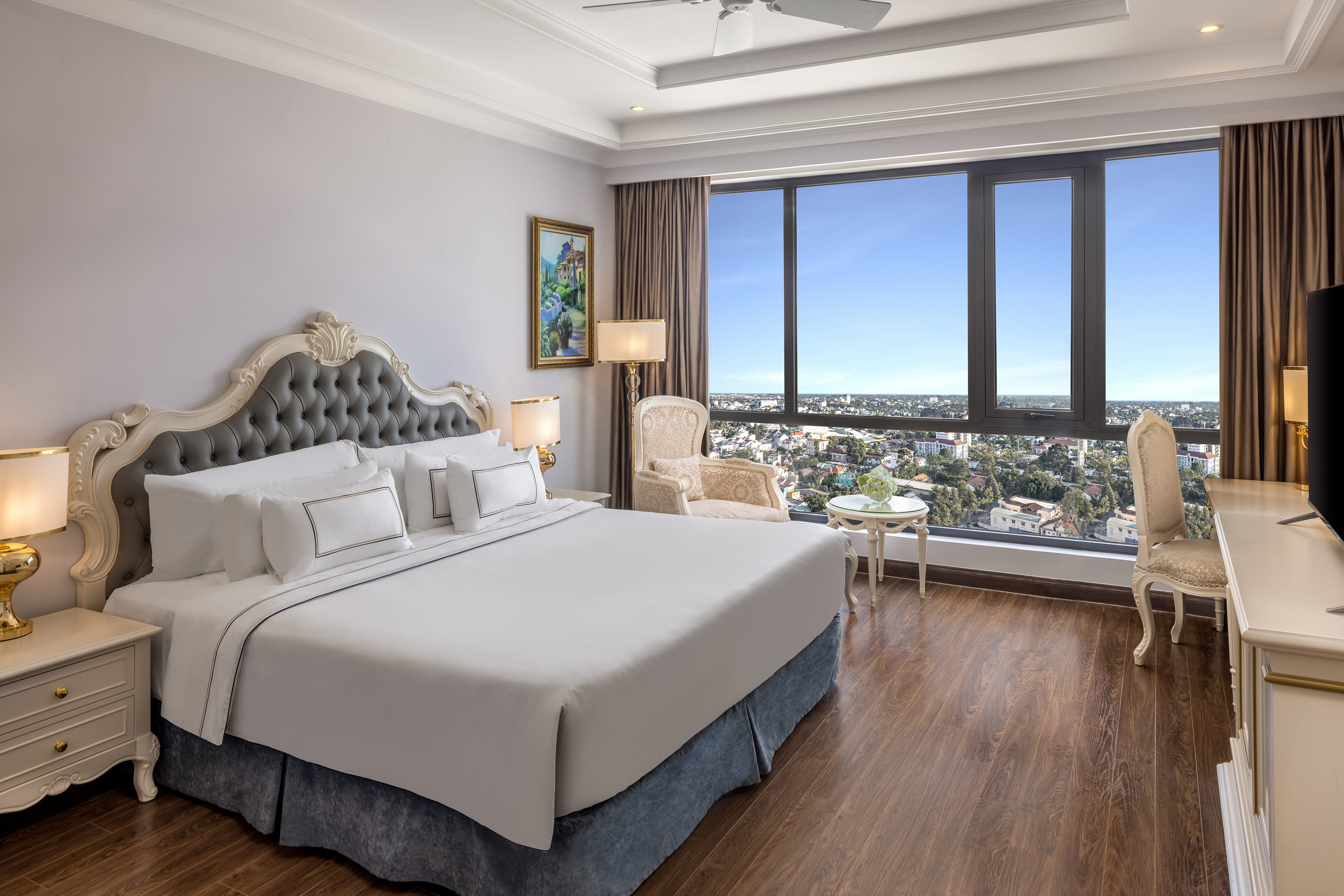 Elegant hotel room with king bed, ornate headboard, and panoramic city view.