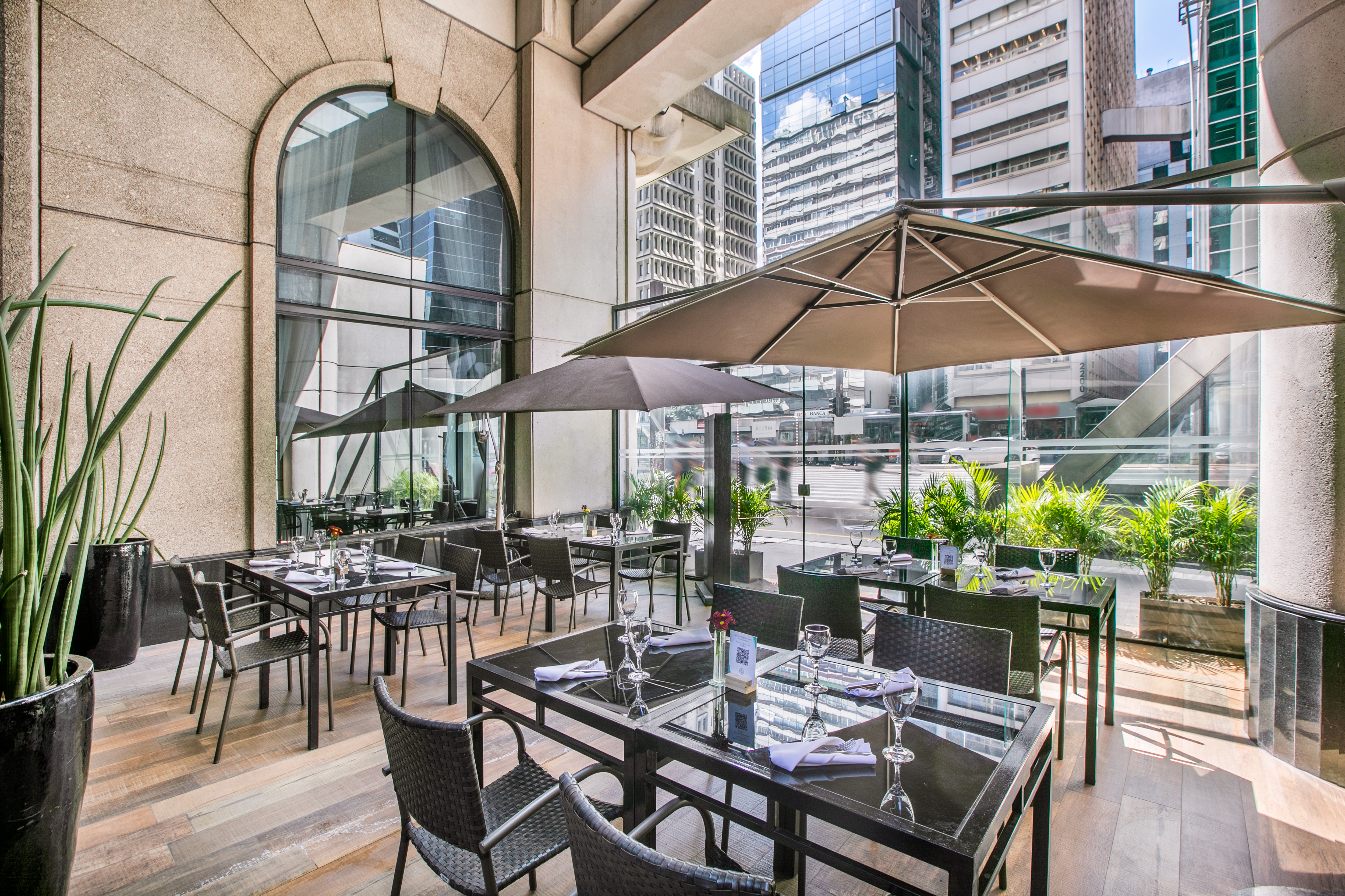 Modern outdoor dining patio with umbrellas and a city view.