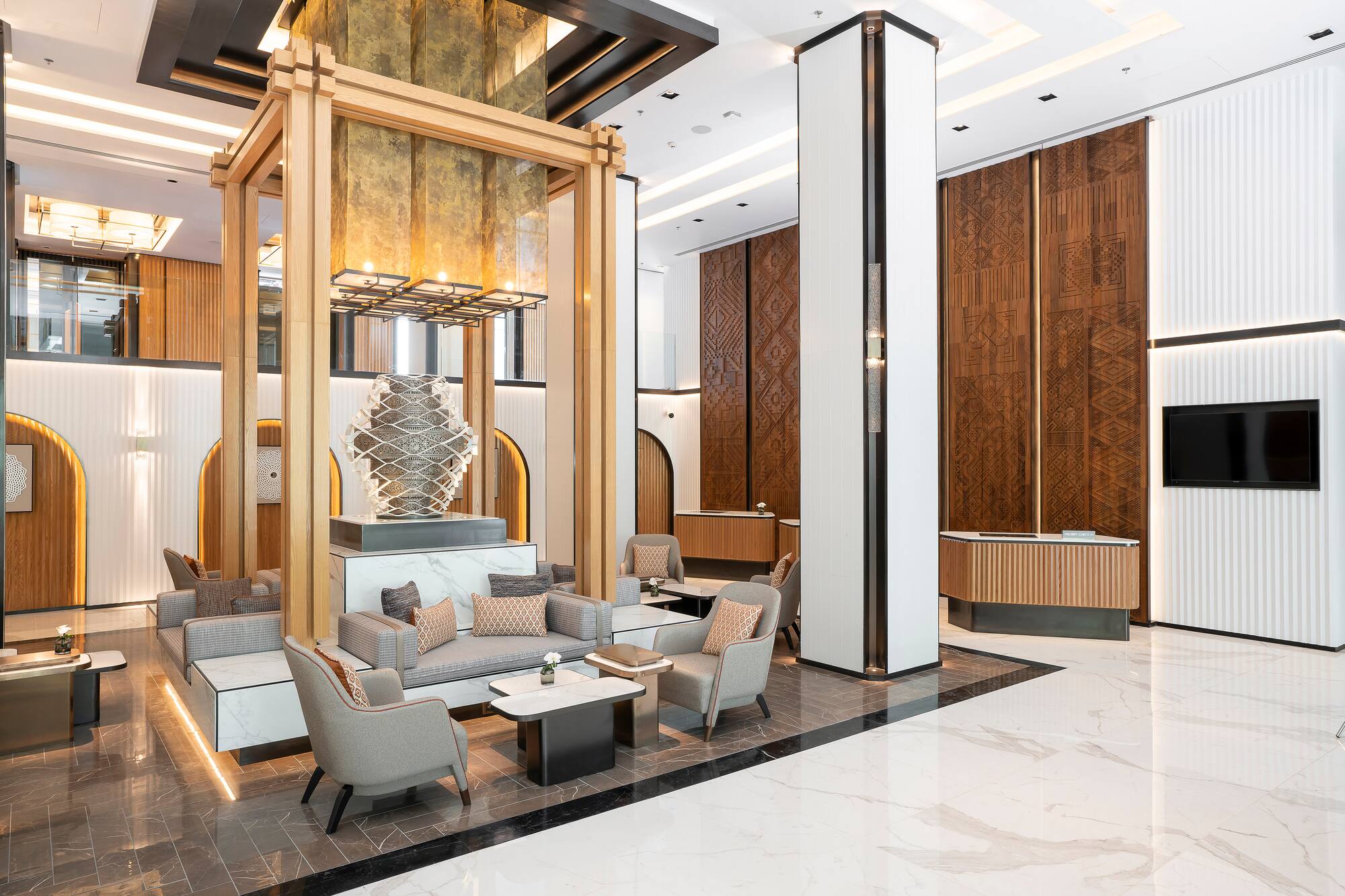 Luxury hotel lobby, modern design with wood accents, marble, and comfy seating.
