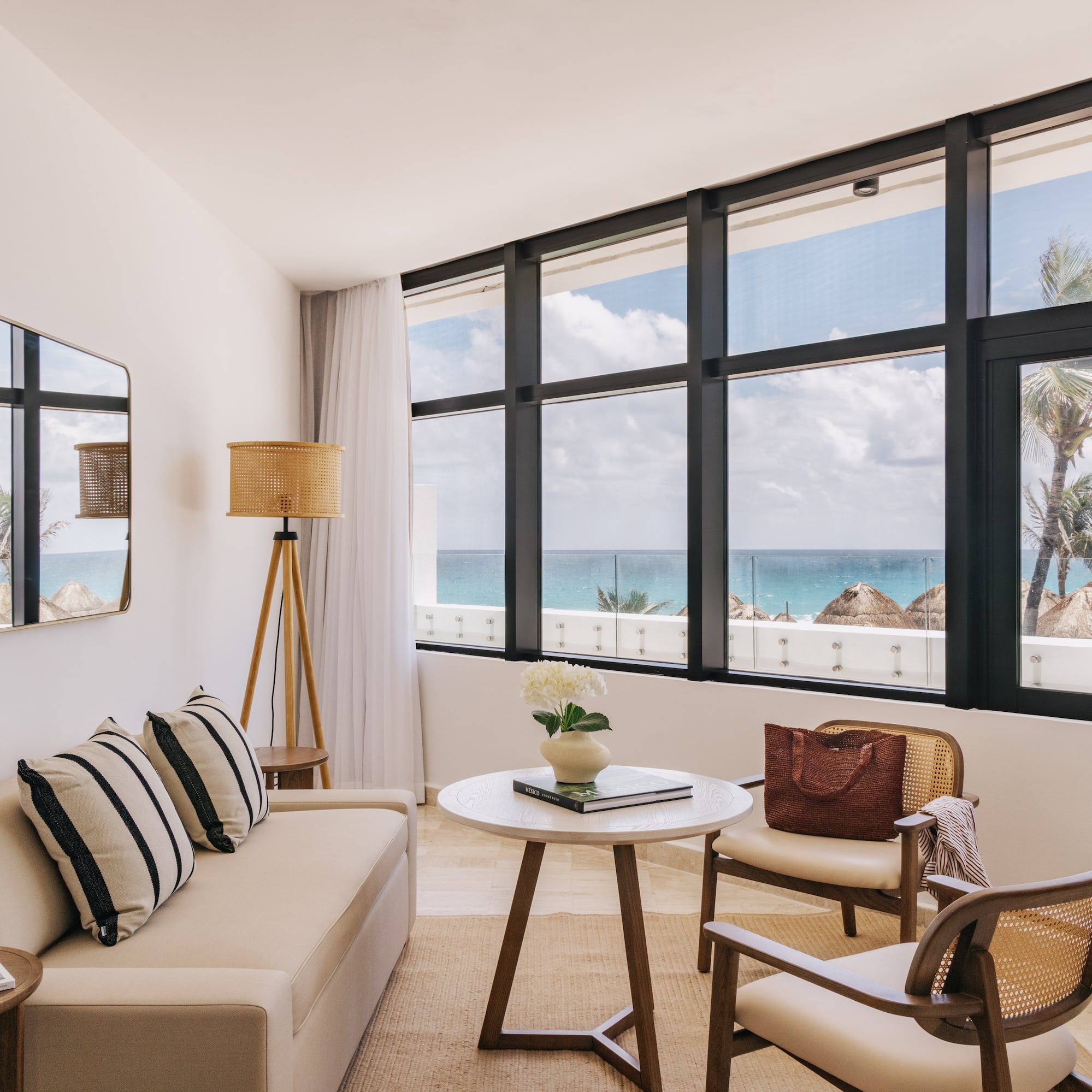 Bright oceanfront hotel living room with palm tree views and modern decor.