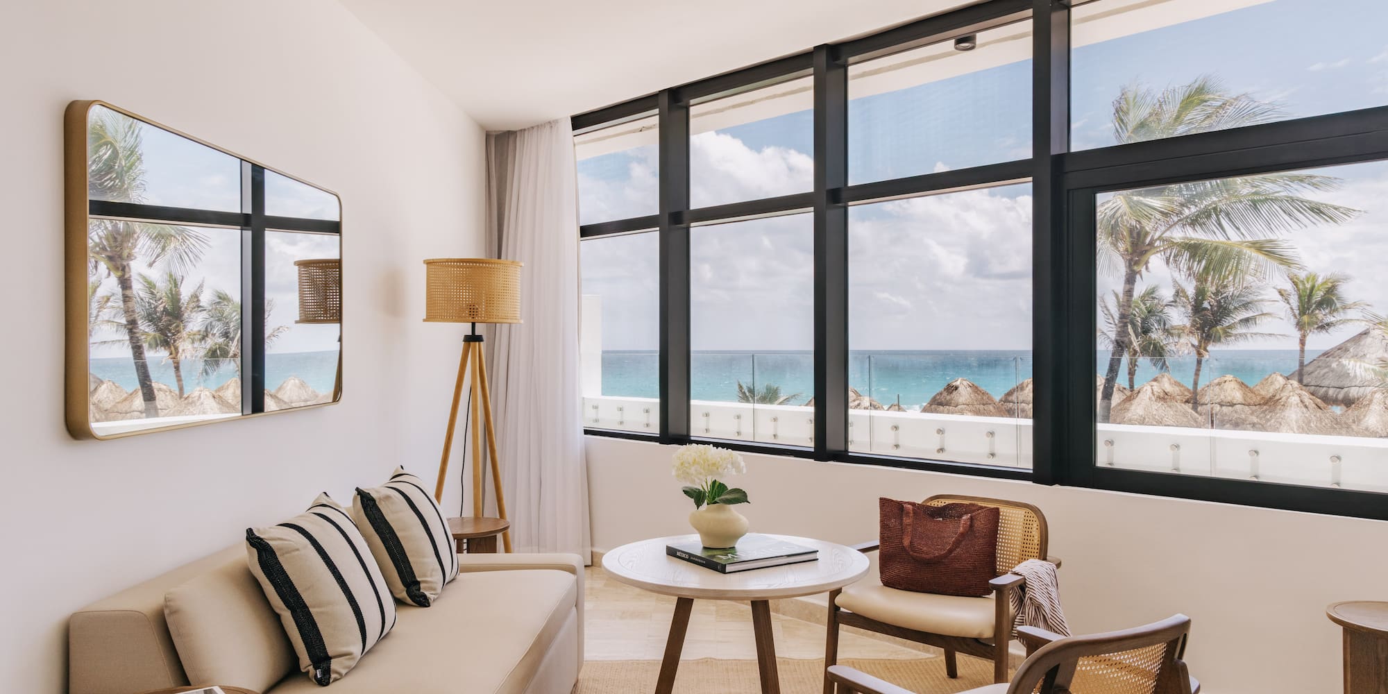 Bright oceanfront hotel living room with palm tree views and modern decor.