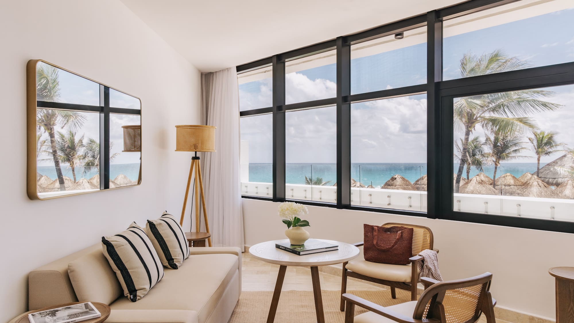 Bright oceanfront hotel living room with palm tree views and modern decor.