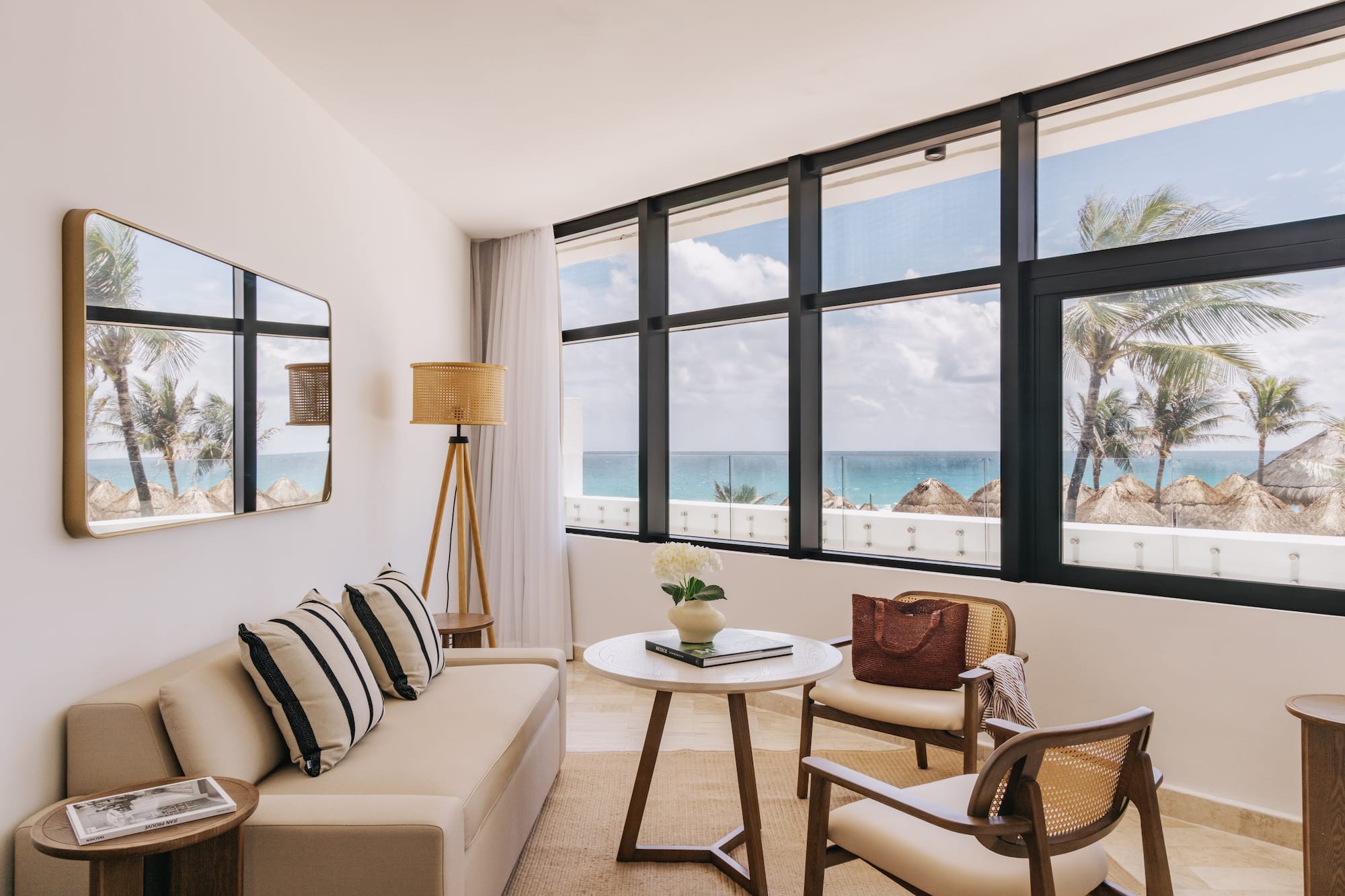 Bright oceanfront hotel living room with palm tree views and modern decor.